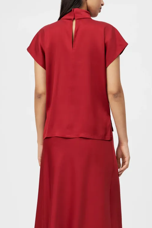 חולצה מבית המותג DRYKORN, בעיצוב קז'ואל-אלגנטי, מבד סאטן איכותי. גזרה נינוחה, עם שרוולים קצרים, וצווארון עומד בסגירת כפתור אחורית.הרכב: 96% אצטט, 4% אלסטןהדוגמנית בגובה 1.78 ולובשת מידה 2 של דרייקורן.