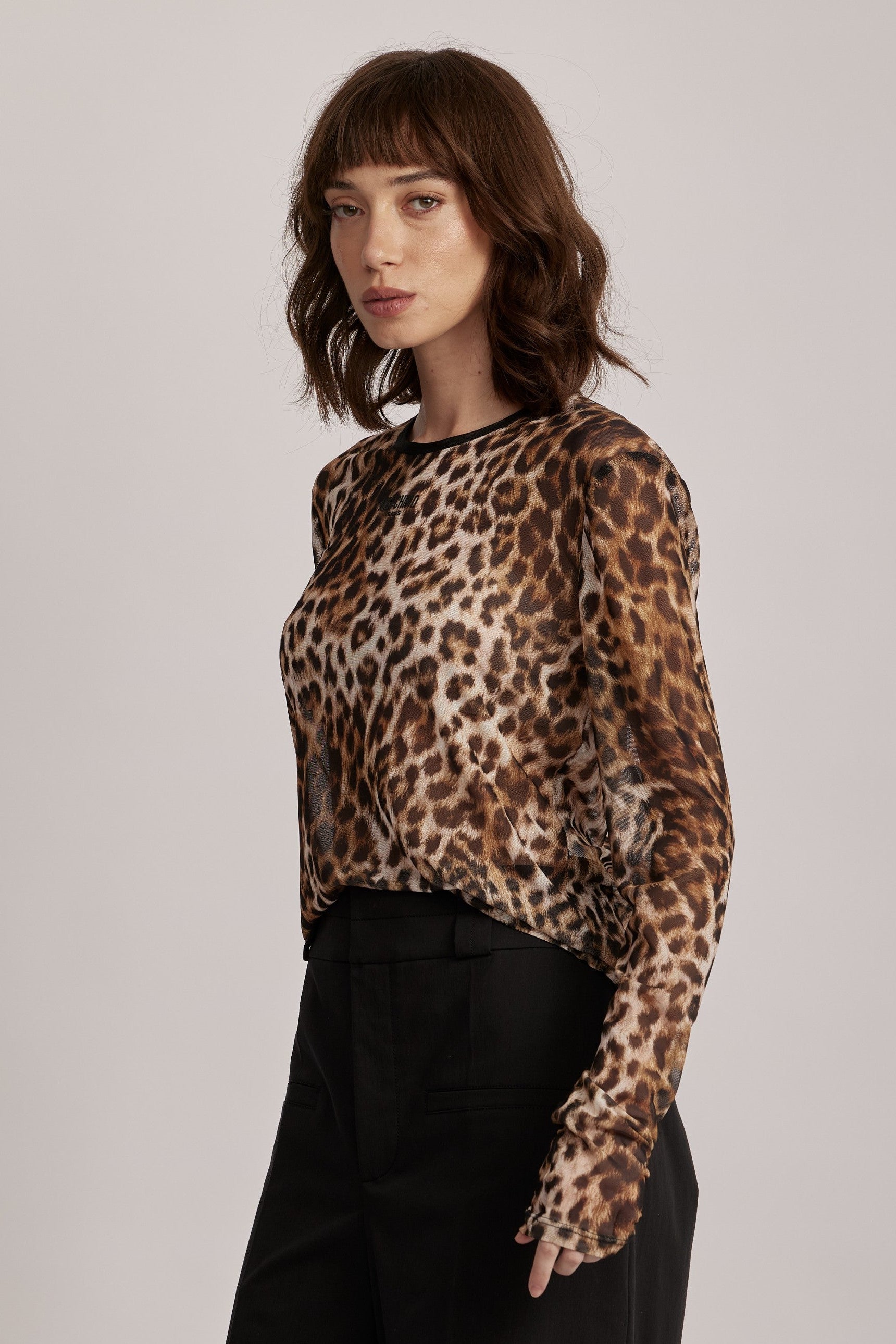 חולצה מליין MOSCHINO JEANS של המותג האיטלקי מוסקינו.החולצה עשויה בד רשת שקפקף בהדפס מנומר, גזרה צמודה לגוף, עם שרוולים ארוכים וצווארון עגול. לוגו המותג מוטבע בחזית.הרכב: 95% פוליאסטר, 5% אלסטןהדוגמנית בגובה 1.75 ולובשת מידה 42 של MOSCHINO