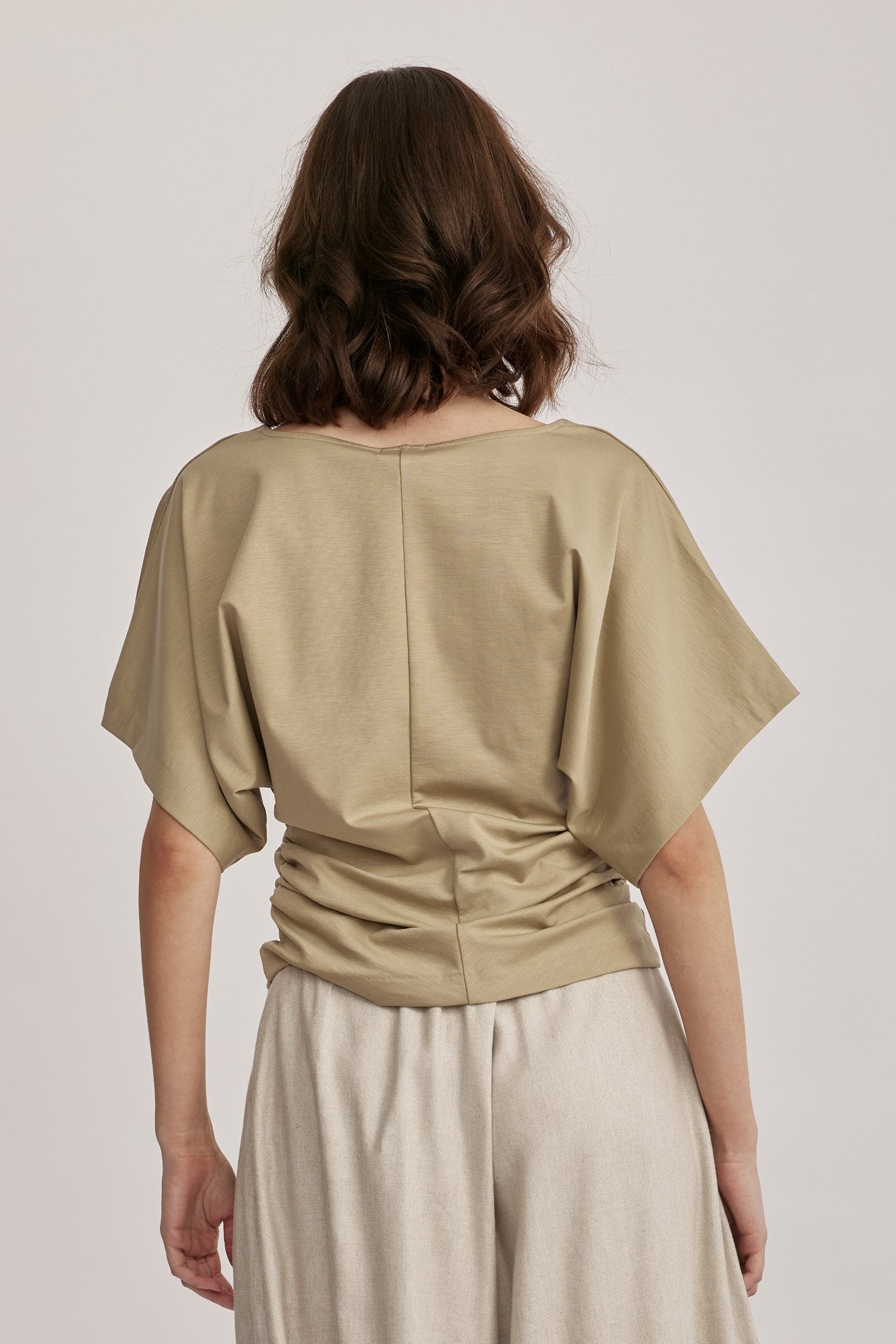 חולצה מבית המותג DRYKORN, מבד רך ונעים. גזרה נינוחה, עם שרוולי עטלף קצרים, צווארון וי, דוגמת כיווצים בצידי החולצה, ותפר אמצעי מודגש בחזית.הרכב: 73% ליוסל, 23% פוליאמיד, 4% אלסטןהדוגמנית בגובה 1.78 ולובשת מידה S של דרייקורן.