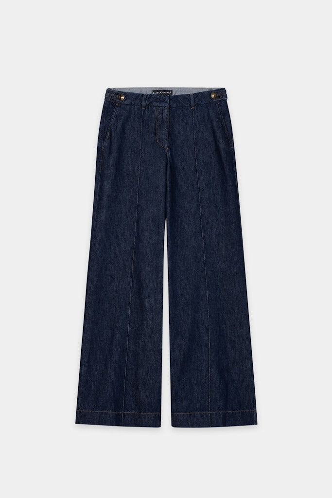 ג'ינס רחב מבית המותג Luisa Cerano, מבד דנים אותנטי, רך ונעים. מכנסיים בגזרת Wide Leg נוחה ואופנתית, עם שני כיסי צד ושני כיסי צ'ינו אחוריים, תפרים קדמיים מודגשים, עיטור כפתורים דקורטיביים במותן, לולאות לחגורה, וסגירה נסתרת באמצעות רוכסן וכפתור.הרכב בד: 81% כותנה, 19% ליוסל (Tencel)הדוגמנית בגובה 1.78 ולובשת מידה 36 של Luisa Cerano