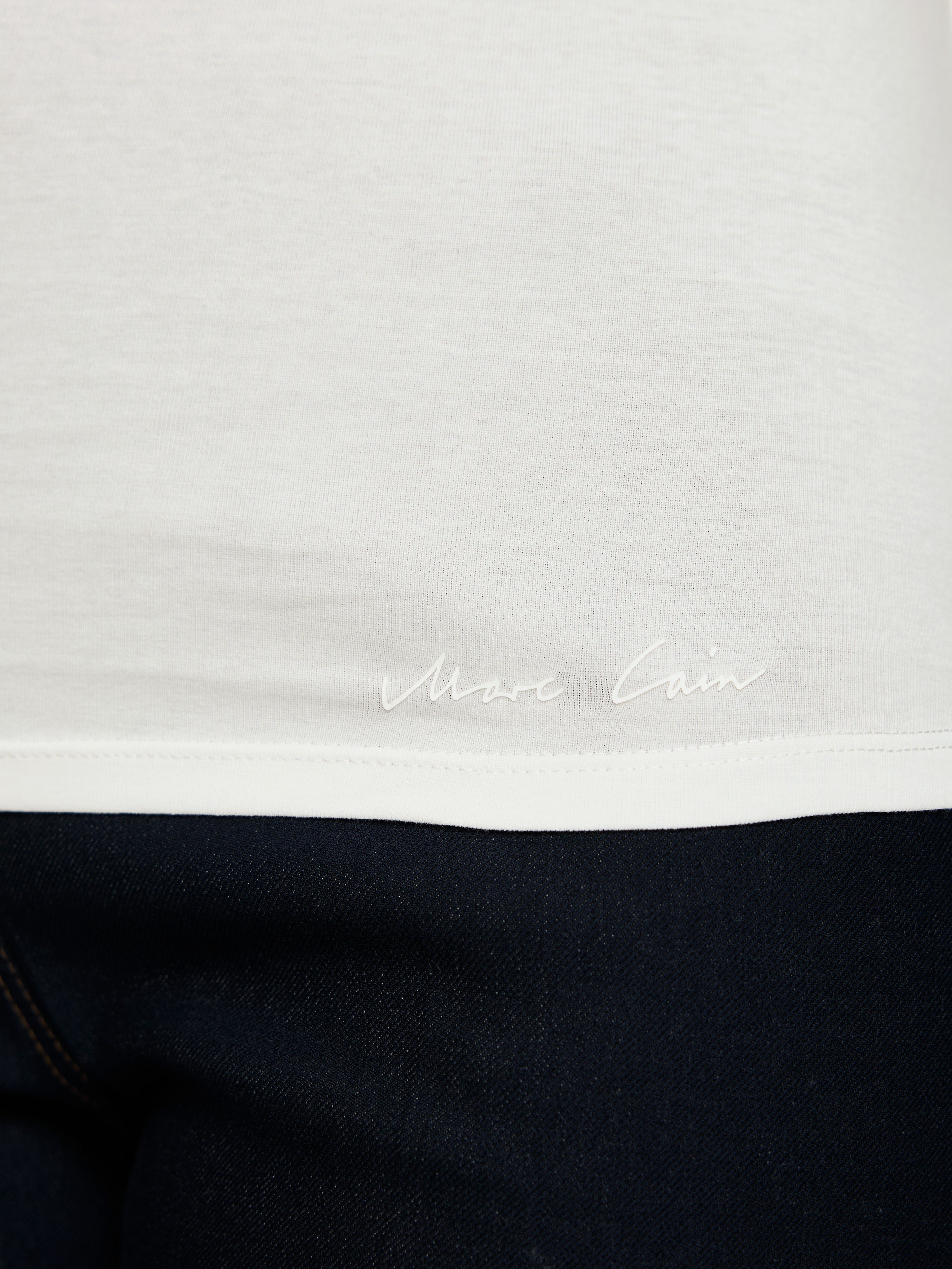 חולצת טי בגזרה צמודה עשויה כותנה נמתחת עם צווארון עגולהרכב: 92% כותנה, 8% אלסטןהדוגמנית בגובה 1.79 ולובשת מידה 3 של מארק קיין