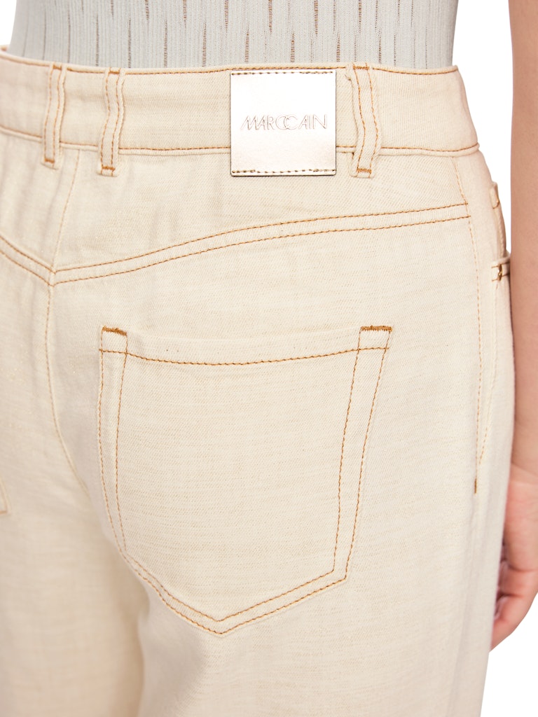 מכנסי ג'ינס בגזרת Wide Leg מתרחבת מאזור קו המותן ועד למכפלת, עם מותן גבוהה ורגל ארוכה.המכנסיים עשויים תערובת כותנה ויסקוזה אלסטית ורכה, לנוחות מקסימלית, בשילוב חוט לורקס המעניק להם ברק עדין, ותפרים מודגשים בצבע זהב להשלמת הטאץ' האלגנטי. עיצוב 5 כיסים קלאסי, לולאות לחגורה, וסגירה באמצעות רוכסן וכפתור.הרכב: 62% כותנה, 32% ויסקוזה, 4% פוליאסטר, 2% פוליאמידהדוגמנית בגובה 1.79 ולובשת מידה 3 של מארק קיין