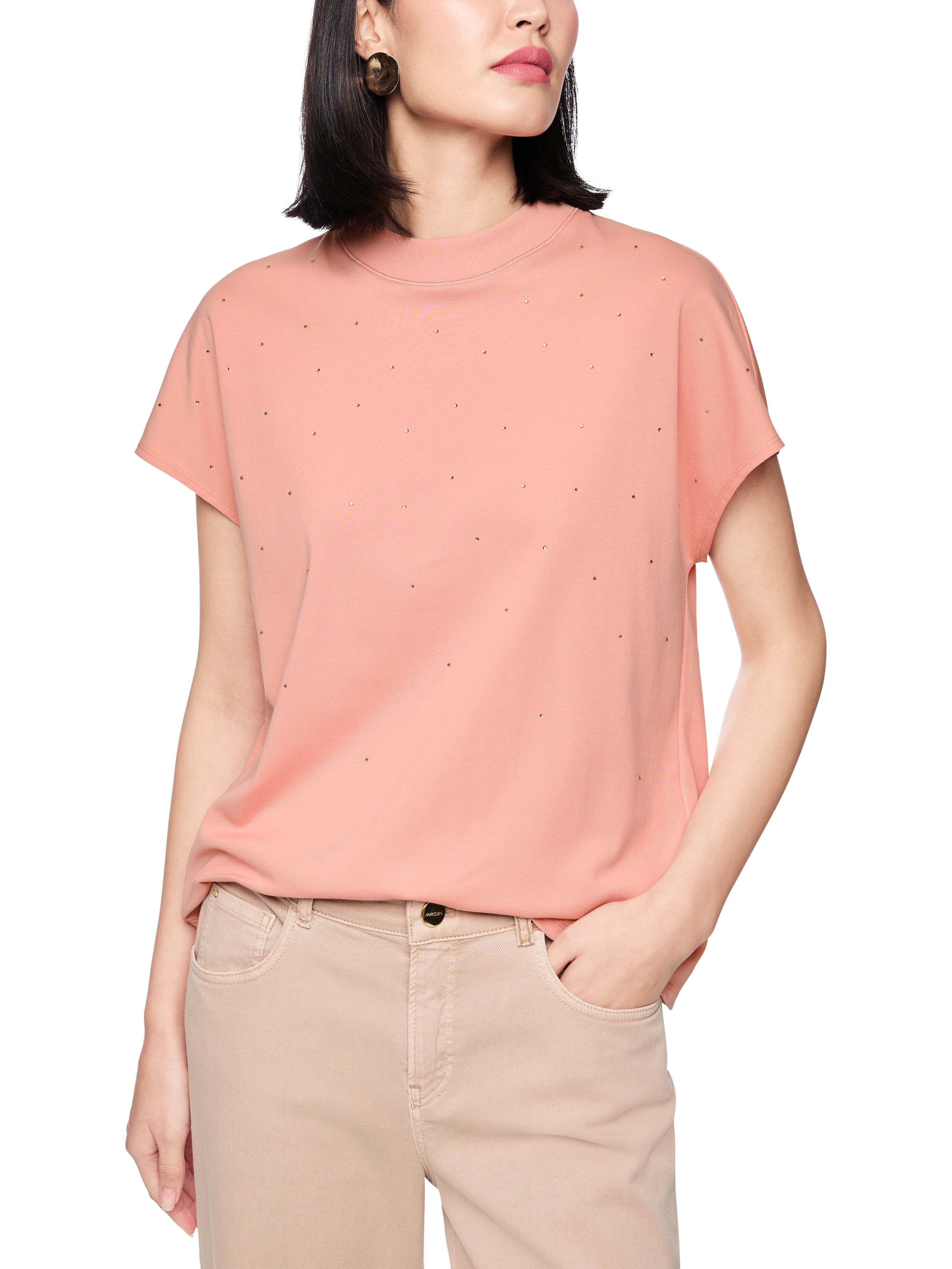 חולצת טי בעיטור אבנים מיניאטוריות בחזית וצווארון עגולהרכב: 95% כותנה, 5% אלסטןהדוגמנית בגובה 1.79 ולובשת מידה 3 של מארק קיין