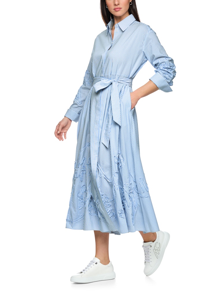 שמלת מידי בעיצוב קז'ואל-אלגנטי, עשויה בד רך וקליל בדוגמת פסים בגווני תכלת ולבן. גזרה נינוחה, עם חגורת מותן נלווית הניתנת לקשירה, להדגשת הצללית הנשית. חצאית מתרחבת, עם נפילה עשירה וזורמת. תוספת דיטייל של עיטור רקמה בדוגמה פרחונית בשרוולים ובחצאית מעניקה לשמלה טוויסט מודרני וייחודי.סגירת כפתורים נסתרת לכל האורך, צווארון קלאסי, ושרוולים ארוכים בסיומת חפתים מכופתרים רחבים המאפשרים התאמת אורך אישית.הרכב: 65% כותנה, 32% פוליאסטר, 3% אלסטןהדוגמנית בגובה 1.79 ולובשת מידה 3 של מארק קיין