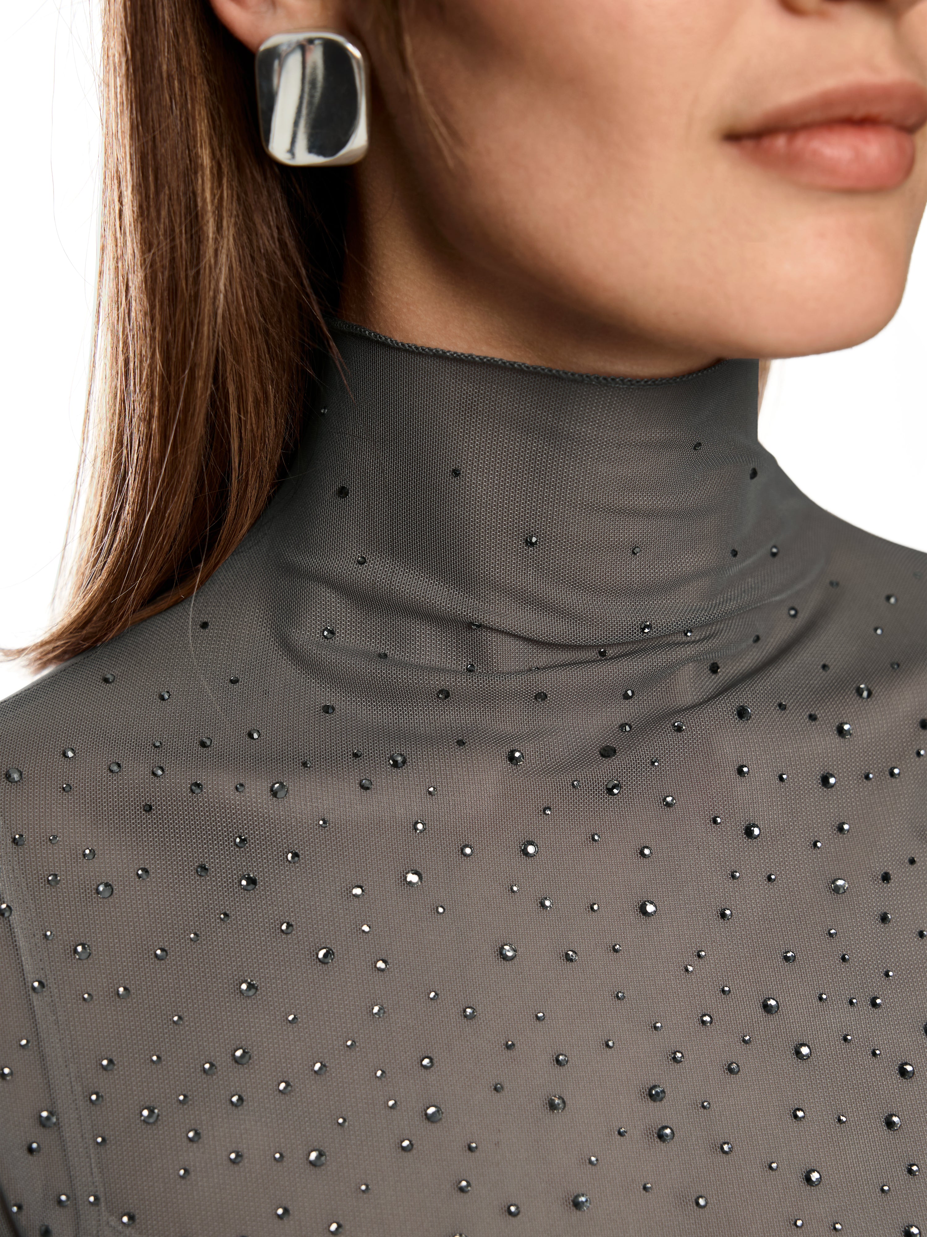 חולצת רשת צמודה עם שרוולים ארוכים וצווארון גבוהמעוטרת באבנים מנצנצות בחזיתהרכב בד: 90% פוליאסטר, 10% אלסטןהדוגמנית בגובה 1.79 ולובשת מידה 3 של מארק קיין