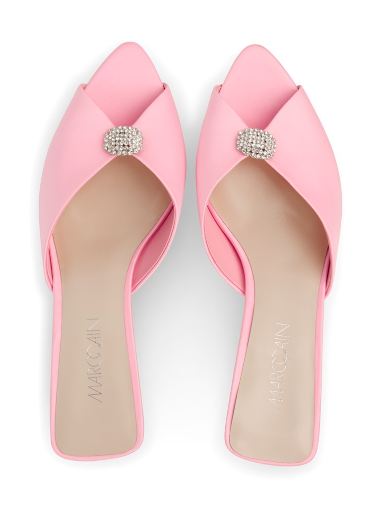 נעלי עקב בעיצוב נשי ואלגנטי, החלק העליון עשוי סאטן, עם עיטור קריסטלי מנצנץ. בסגנון כפכפים, פתוחות בחלקן האחורי, עם פתח לבוהן. עקב קיטן שקוף ומודרני, רפידת עור, וסוליית Thunit עמידה.גובה עקב: 6 ס"מהרכב: 100% פוליאסטר