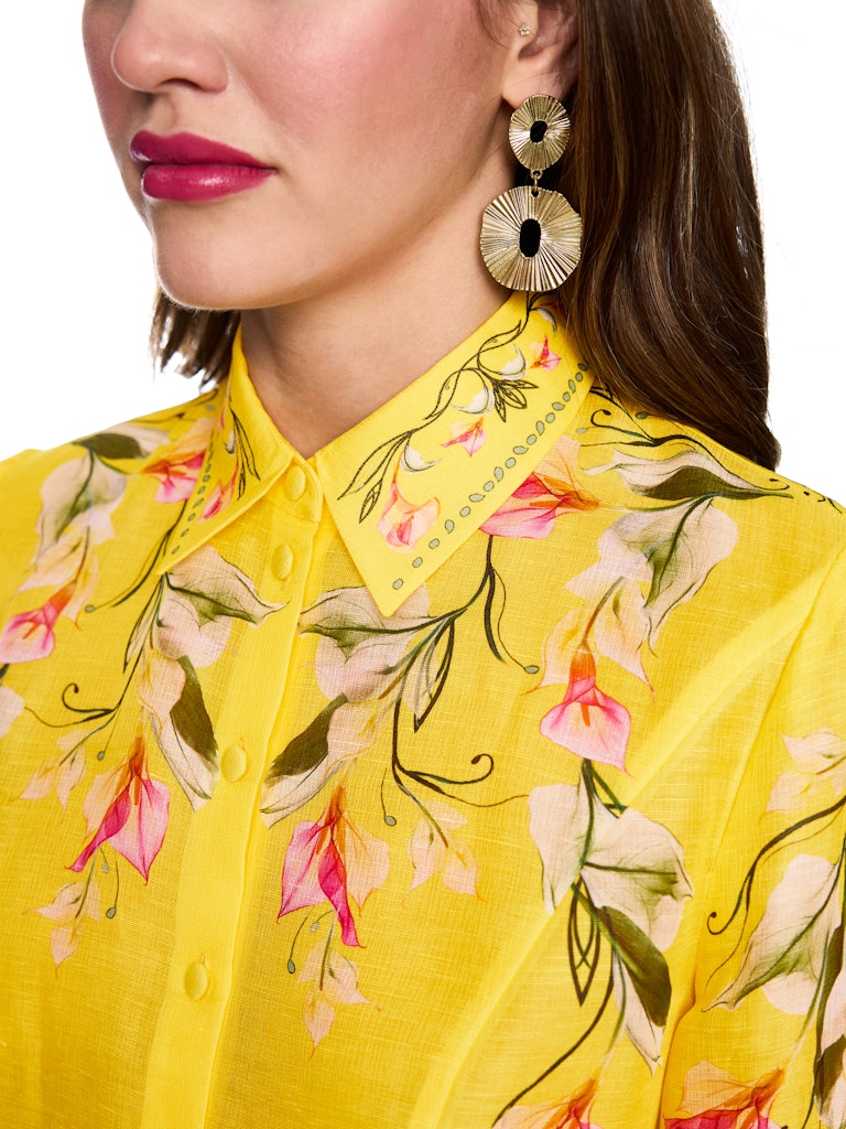 חולצה מכופתרת קלילה ואלגנטית, עשויה תערובת פשתן ומשי איכותית ונעימה. גזרה נשית ונינוחה, עם צווארון קלאסי, שרוולים ארוכים בסיומת חפתים רחבים מכופתרים, וסגירה באמצעות שורת כפתורים קדמית. הדפס צבעוני של דוגמת פרחי קאלה המעטר את החלק העליון של החולצה, הצווארון, והחפתים, מדגיש את העיצוב הייחודי.הרכב: 55% פשתן, 45% משיהדוגמנית בגובה 1.79 ולובשת מידה 3 של מארק קיין