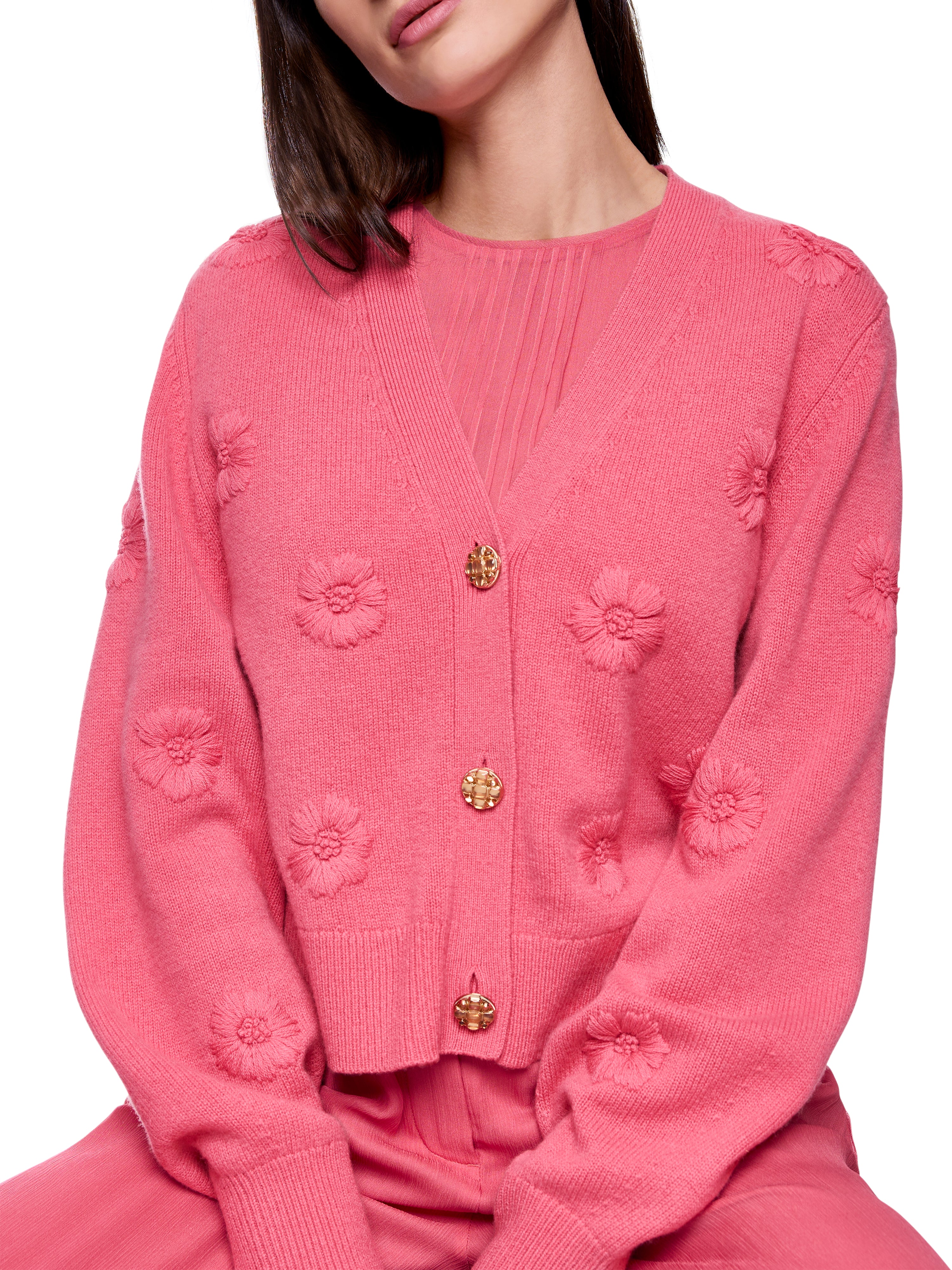 קרדיגן אלגנטי בצבע ורוד עמוק, בגזרה רפויה עם מחשוף V ודוגמת פרחים רקומיםבעיטור כפתורי זהב עם קריסטליםהרכב בד: 90% צמר בתולי, 10% קשמירהדוגמנית בגובה 1.79 מ' ולובשת מידה 3 של מארק קיין