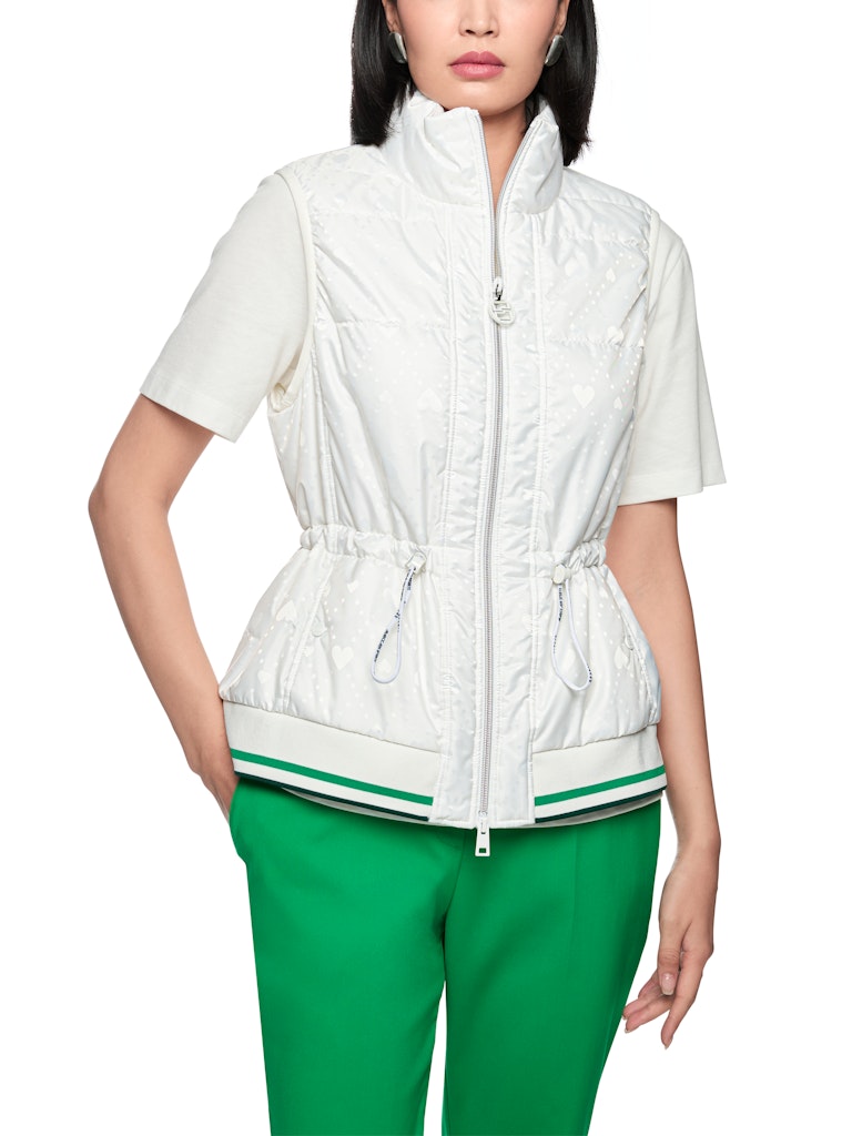 וסט מרופד בעיצוב ספורטיבי, עם הדפס בדוגמת לבבות. גזרה ישרה, עם שרוכי גומי מתכווננים במותניים להתאמה אישית, צווארון עומד, כיסים צדדיים הניתנים לסגירה, ורוכסן דו כיווני, בגימור מנג'ט ארוג בדוגמת פסים צבעוניים.הרכב: 65% פוליאמיד, 35% פוליאסטרהדוגמנית בגובה 1.79 ולובשת מידה 3 של מארק קיין