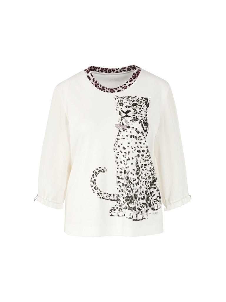 חולצה בגזרה ישרה ונינוחה, עשויה מבד כותנה גמיש ונעים, עם הדפס חזיתי של נמר, וצווארון עגול בגימור בד בדוגמה מנומרת. שרוולי החולצה באורך 3/4, מבד דק וזורם, עם חפתים אלסטיים הניתנים לכיוונון והתאמה אישית.הרכב: חולצה- 94% כותנה, 6% אלסטן, שרוולים- 59% פוליאסטר, 41% פוליאסטר ממוחזרהדוגמנית בגובה 1.79 ולובשת מידה 3 של מארק קיין