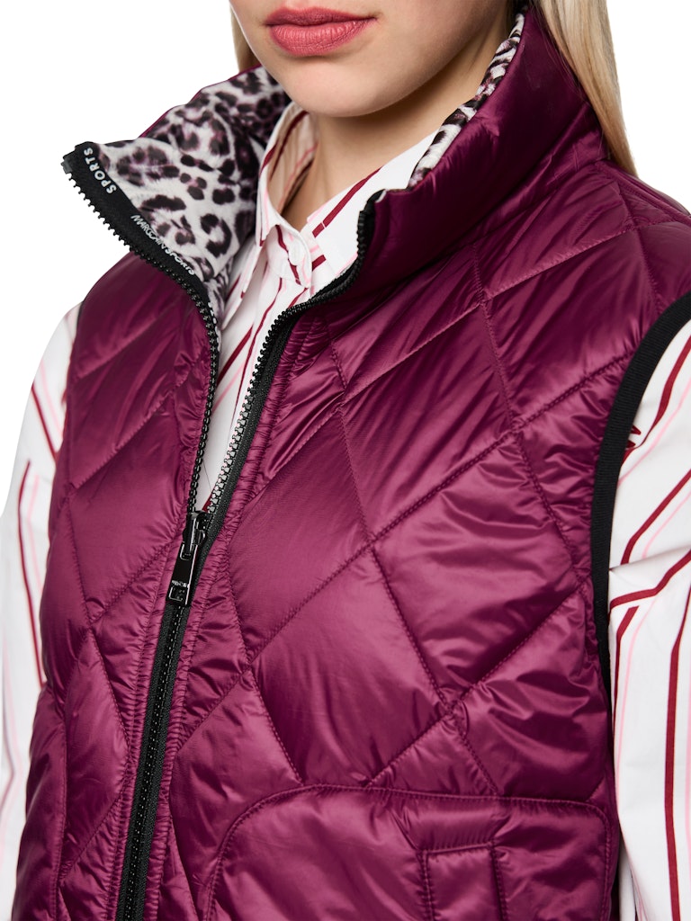 וסט קווילט דו צדדי מרופד ומחמם, צידו האחד של הוסט בגוון בורדו, וצידו השני בהדפס מנומר. עם צווארון גבוה, שני כיסים צידיים נסגרים, וסגירת רוכסן דו כיווני.הרכב: 100% פוליאסטר ממוחזרהדוגמנית בגובה 1.79 ולובשת מידה 3 של מארק קיין