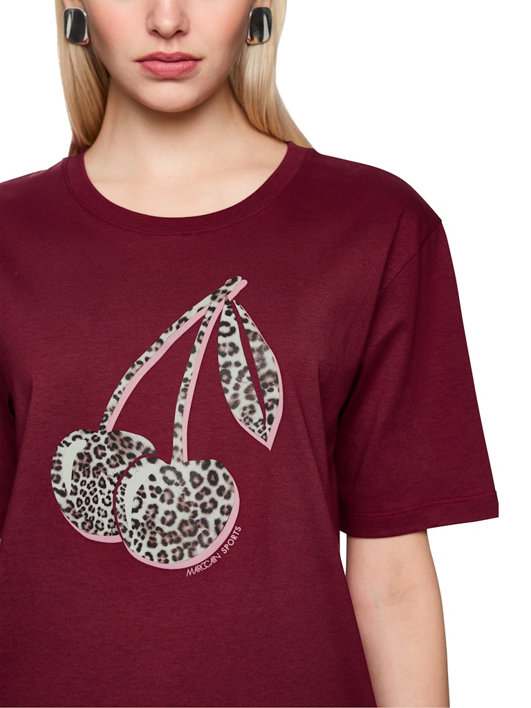 חולצת טישירט בגזרה ישרה ונינוחה, עם שרוולים קצרים וצווארון עגול, והדפס חזיתי של דובדבנים בדוגמה מנומרת.הרכב: 100% כותנה אורגניתהדוגמנית בגובה 1.79 ולובשת מידה 3 של מארק קיין