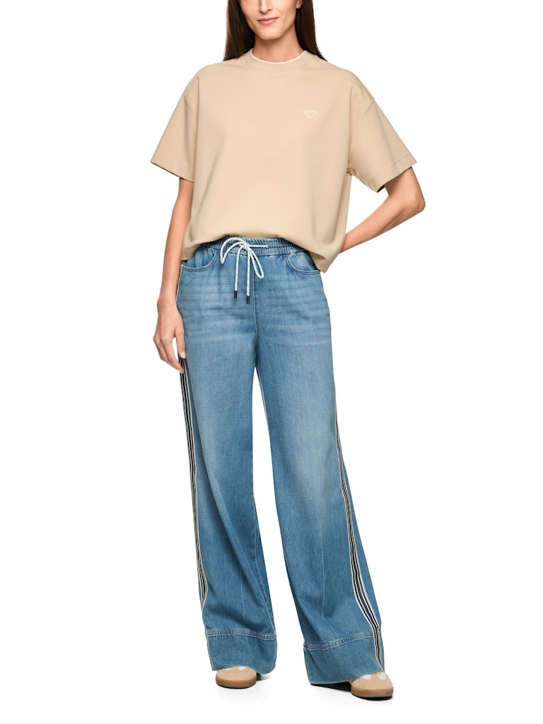 מכנסי ג'ינס בגזרת Wide Cut, רחבה ומשוחררת, עם מותן גבוהה, עשויים בד רך וזורם.המכנסיים בעיצוב ספורטיבי, עם רצועת מותן אלסטית ורחבה עם שרוך קשירה, תוספת דיטיילס של פס בד לאורך הרגל ורקמה על הכיס האחורי, 2 כיסים צידיים ו-2 כיסים אחוריים.הרכב: 64% כותנה, 36% ליוסלהדוגמנית בגובה 1.79 ולובשת מידה 3 של מארק קיין