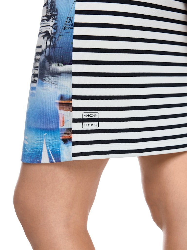 שמלת מיני בגזרה צמודה לגוף, מבד נעים ואלסטי בטקסטורת פסי ריב, המשלבת חלק קדמי בהדפס בדוגמת מוטיבים מעולם הספינות, וחלק אחורי בדוגמת פסים. עם צווארון עגול, וללא שרוולים.הרכב: 94% כותנה, 6% אלסטןהדוגמנית בגובה 1.79 ולובשת מידה 3 של מארק קיין