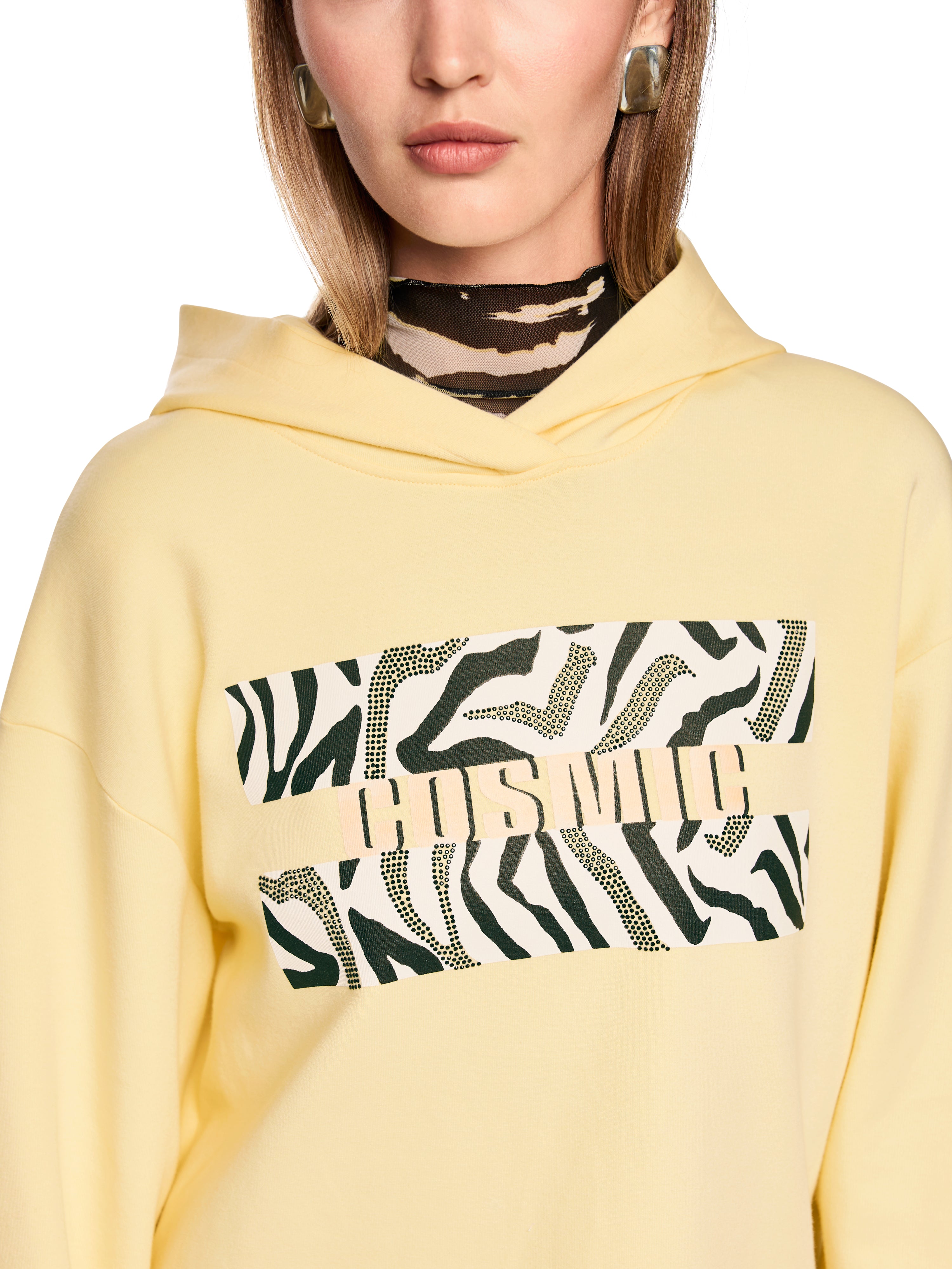 סווטשירט קז'ואל עשוי כותנה עם קפוצ'ון והדפסהרכב: 100% כותנההדוגמנית בגובה 1.79 ולובשת מידה 3 של מארק קיין