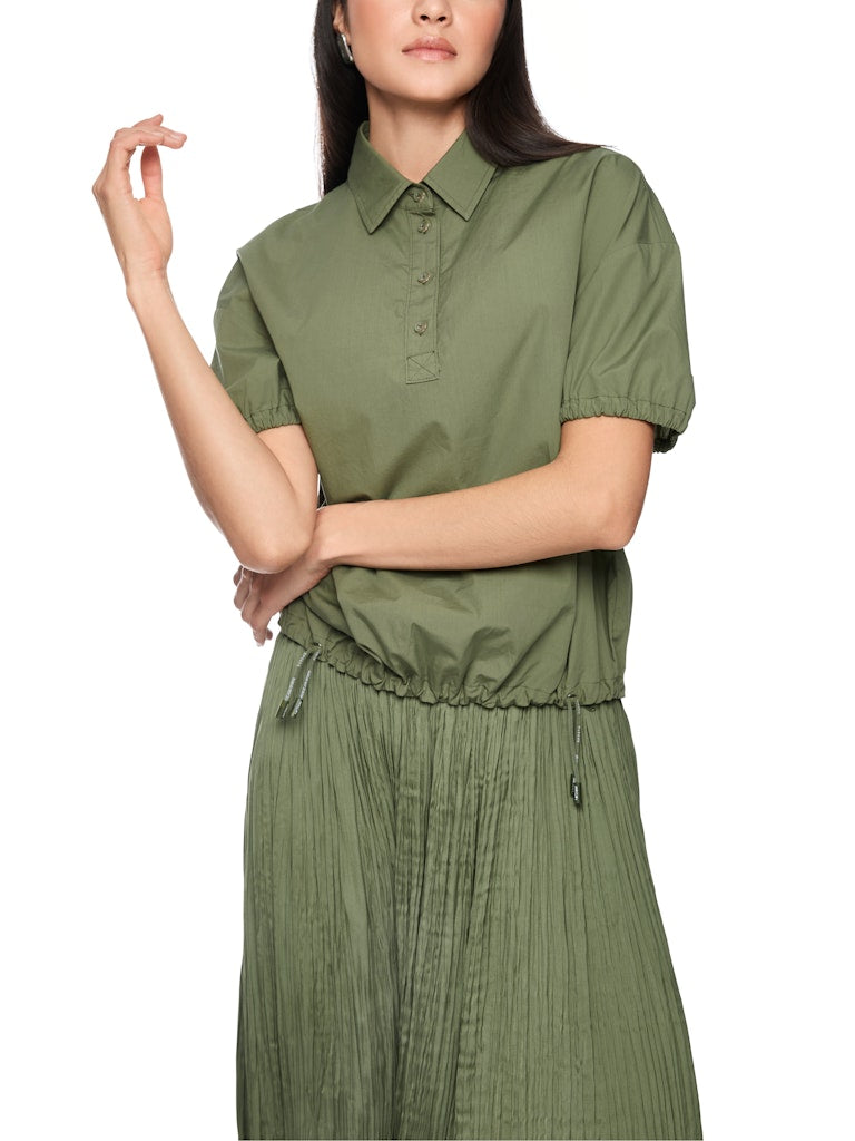 חולצה קצרה בגזרה רחבה ונינוחה, עשויה כותנה אורגנית טהורה, רכה ונעימה במיוחד. לחולצה צווארון קלאסי עם סגירת כפתורים, שרוולים קצרים ותפוחים עם סיומת כיווצים אלסטית, ומכפלת עם שרוכי קשירה בסגנון ספורטיבי, המאפשרים התאמת רוחב אישית.הרכב: 100% כותנה אורגניתהדוגמנית בגובה 1.79 ולובשת מידה 3 של מארק קיין