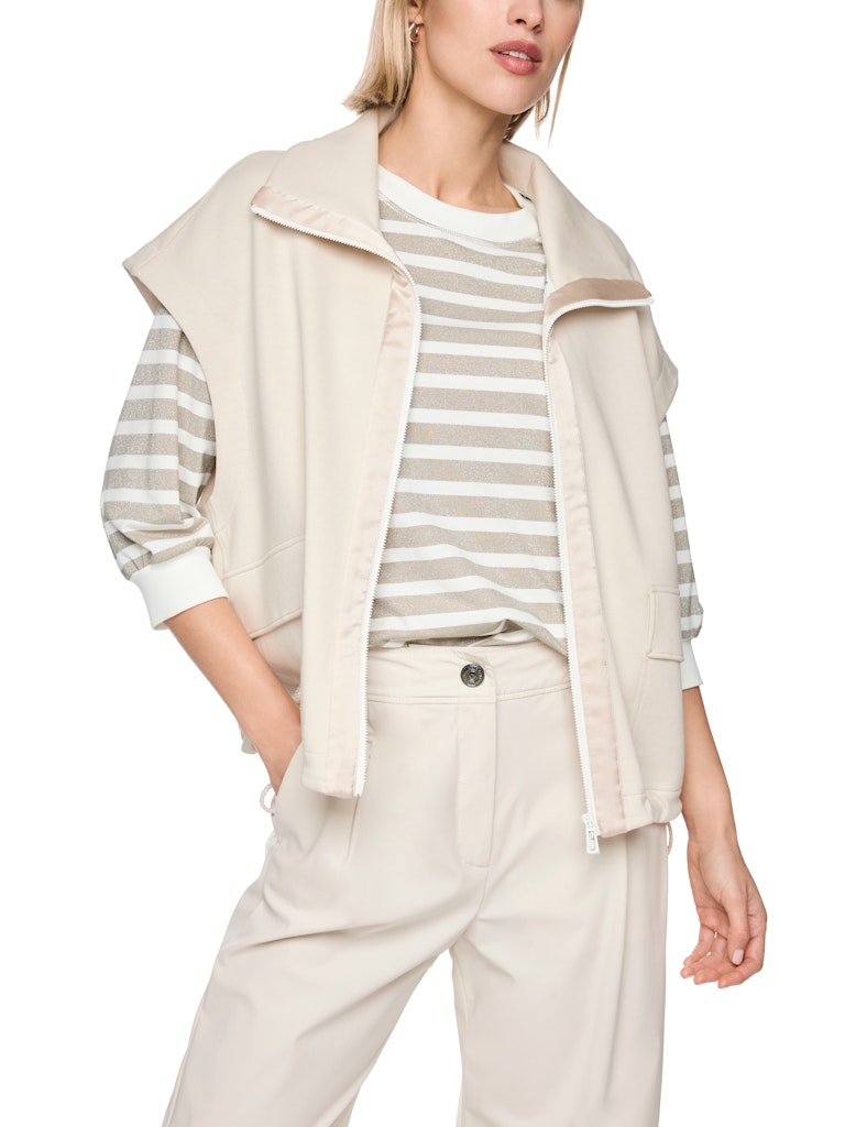 וסט דק ללא בטנה עם רוכסן דו צדדי. שרוולים רחבים וקצרים ושרוכי כיווצים במותניים ליצירת מראה בלוזון.לוסט צווארון דומיננטי שניתן לקפל או לרכוס גבוה. לאורך הרוכסן פסי סאטן. הרכב: 77% כותנה 18% פוליאמיד 5% אלסטן הדוגמנית בגובה 1.79 ולובשת מידה 3
