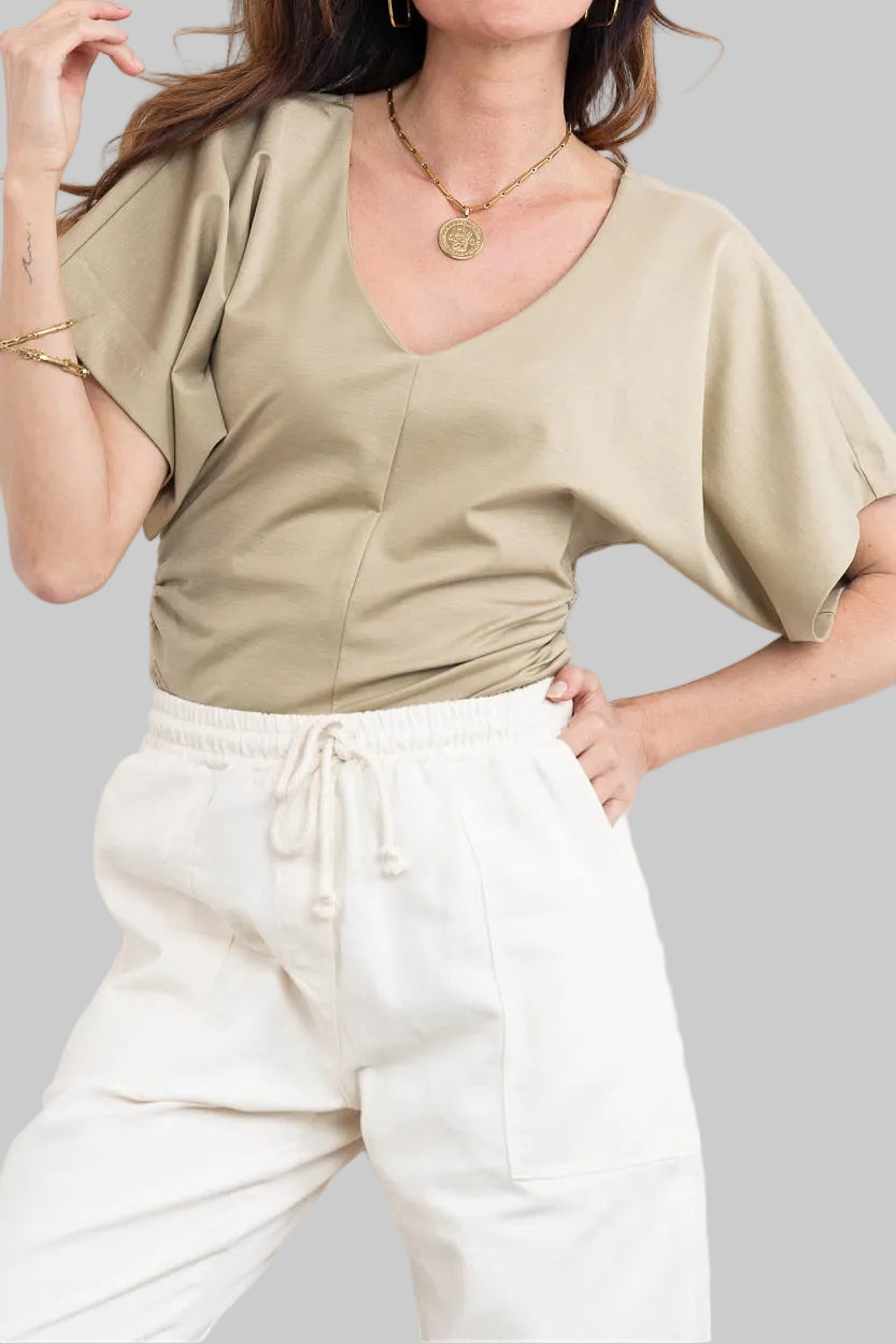 חולצה מבית המותג DRYKORN, מבד רך ונעים. גזרה נינוחה, עם שרוולי עטלף קצרים, צווארון וי, דוגמת כיווצים בצידי החולצה, ותפר אמצעי מודגש בחזית.הרכב: 73% ליוסל, 23% פוליאמיד, 4% אלסטןהדוגמנית בגובה 1.78 ולובשת מידה S של דרייקורן.