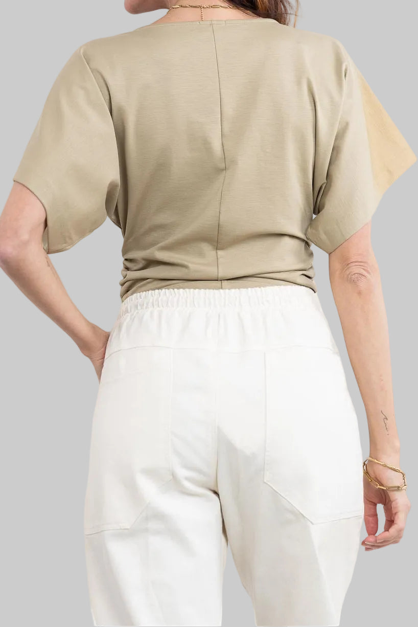 חולצה מבית המותג DRYKORN, מבד רך ונעים. גזרה נינוחה, עם שרוולי עטלף קצרים, צווארון וי, דוגמת כיווצים בצידי החולצה, ותפר אמצעי מודגש בחזית.הרכב: 73% ליוסל, 23% פוליאמיד, 4% אלסטןהדוגמנית בגובה 1.78 ולובשת מידה S של דרייקורן.