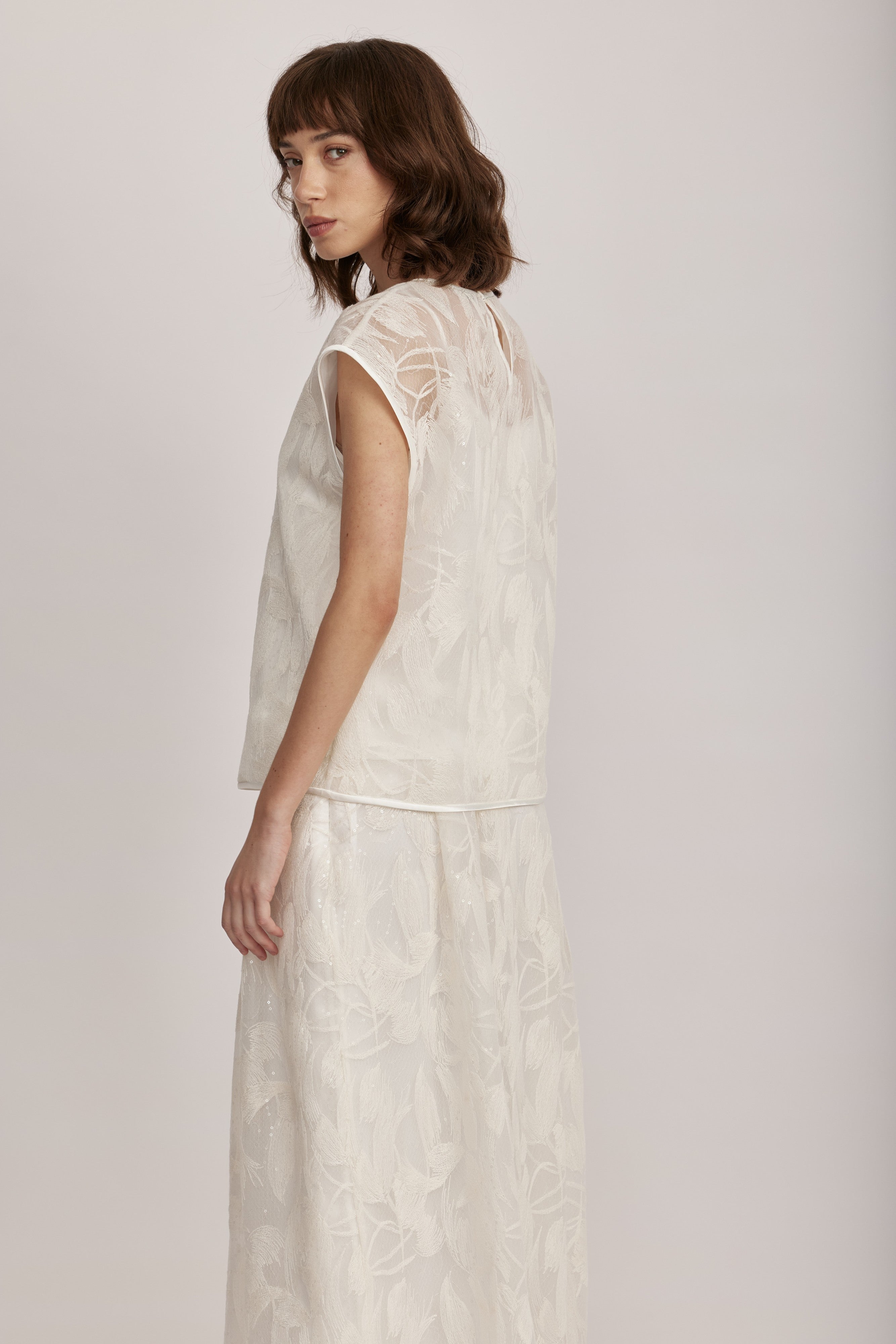 חולצה מקולקציית ה-Runway של המותג האיטלקי PESERICO, בעיצוב דו-שכבתי המשלב בד טול שקוף מעוטר ברקמה עדינה עם פאייטים בדוגמת עלים, ובד אורגנזה דק וקליל בגוון תואם, היוצר משחקי טקסטורה ושקיפויות, ומראה ייחודי.החולצה בגזרה ישרה ומשוחררת, עם שרוולי קאפ קצרים, צווארון עגול, בטנה פנימית, וסגירה באמצעות כפתור בגב.הרכב: טול- 50% פוליאמיד, 50% כותנה, אורגנזה- 100% פוליאסטר, בטנה- 97% פוליאסטר, 3% אלסטןהדוגמנית בגובה 1.75 ולובשת מידה 42 של PESERICO