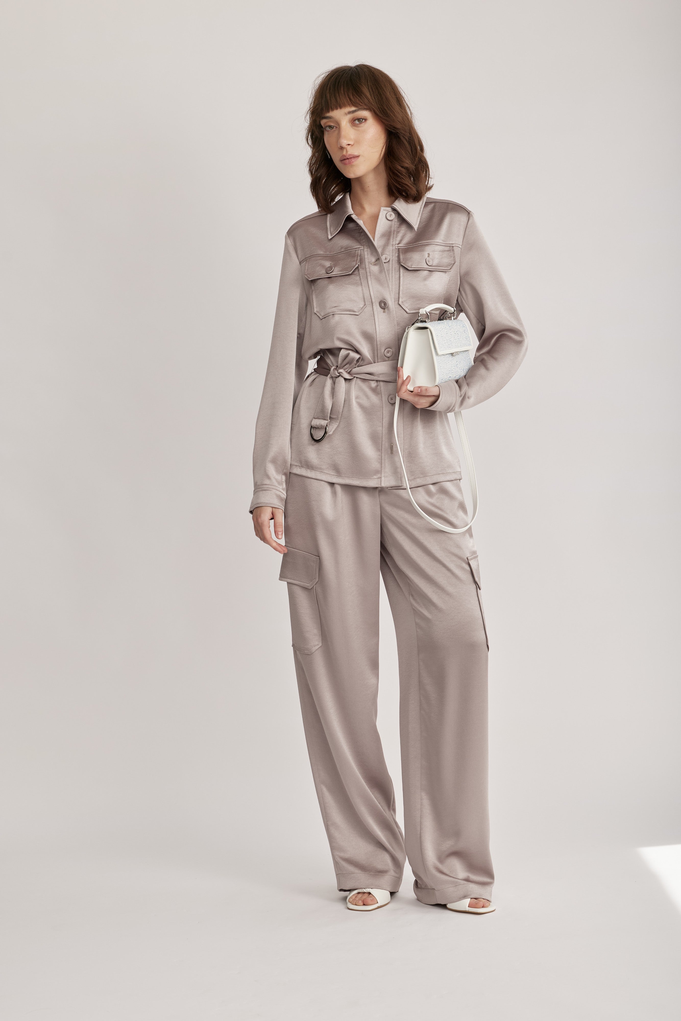 חולצה מבית המותג RIANI בעיצוב מודרני ואלגנטי, מבד סאטן רך וגולש בעל ברק מטאלי עדין, עם חגורת מותן נשלפת, להתאמה אישית ומגוון אפשרויות לבישה. גזרה ישרה, עם צווארון קלאסי, שני כיסי חזה מכופתרים, שרוולים ארוכים בגימור חפתים, וסגירת כפתורים לכל האורך.הרכב: 100% פוליאסטרהדוגמנית בגובה 1.75 ולובשת מידה 36 אירופאית