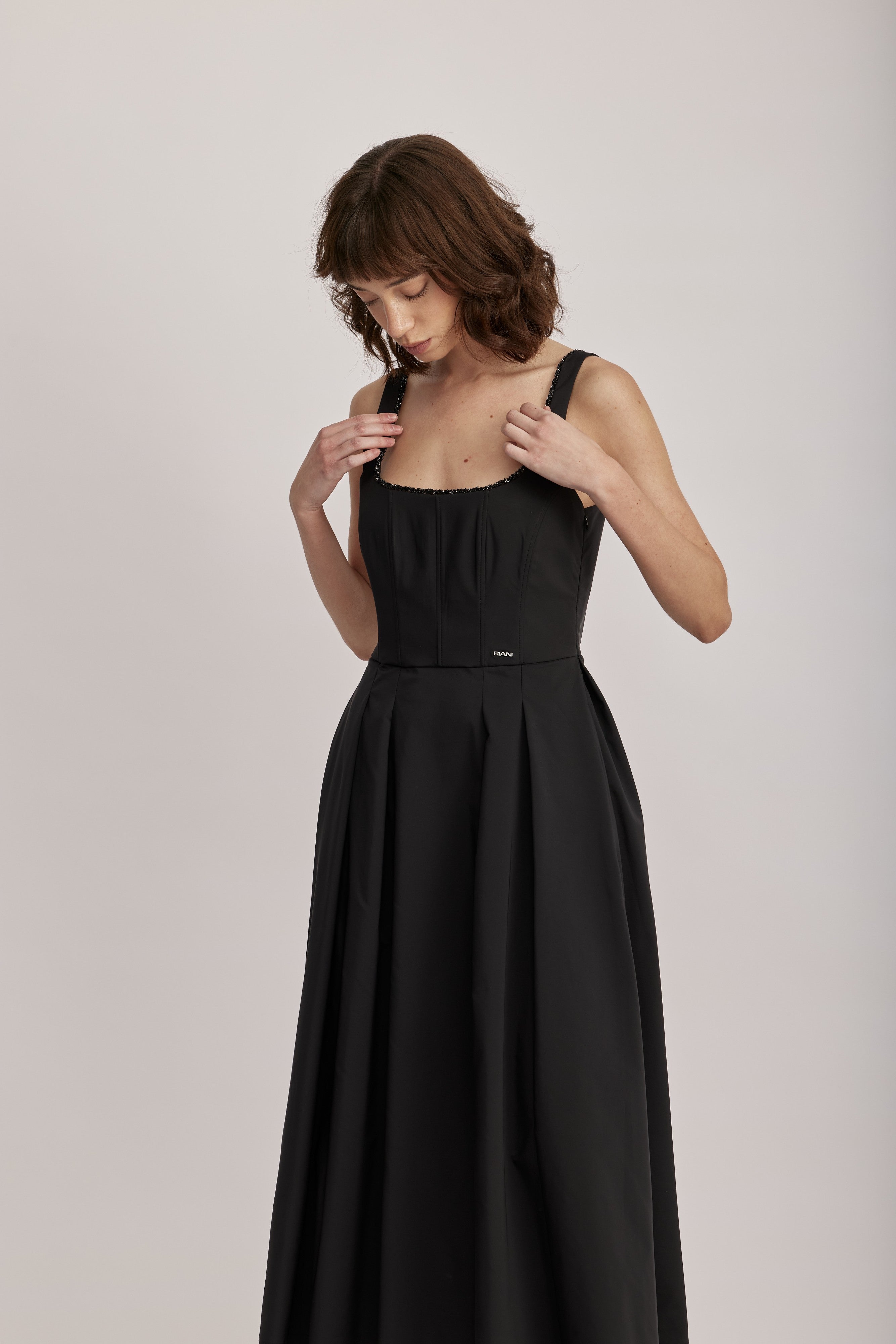 שמלה מבית המותג RIANI, בעיצוב קלאסי. גזרת A עם חצאית קפלים מתרחבת, מבד קליל וזורם. מחשוף מרובע, גב במפתח עמוק, וכתפיות גופיה רחבות ומעוטרות משלימים את העיצוב ויוצרים צללית מודרנית ונשית, וסטייל על זמני שיתאים לכל אירוע. עם כיסי צד וסגירה באמצעות רוכסן בגב.הרכב: 100% פוליאסטרהדוגמנית בגובה 1.75 ולובשת מידה 36 אירופאית
