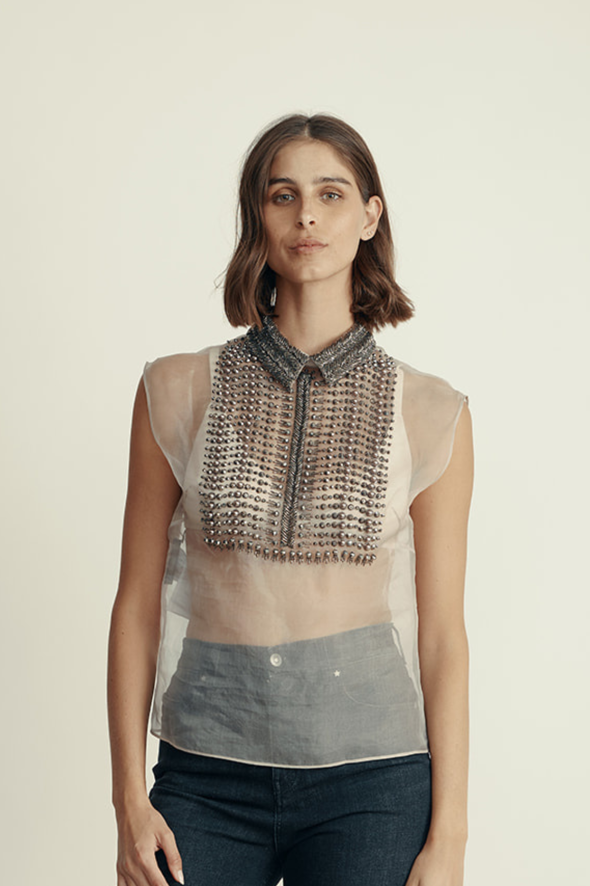 חולצת משי שקופה ללא שרוולים, מעוטרת בניטים וחרוזים בחלק הקידמיהרכב: 100% משיהדוגמנית בגובה 1.80 ולובשת מידה 42 איטלקית