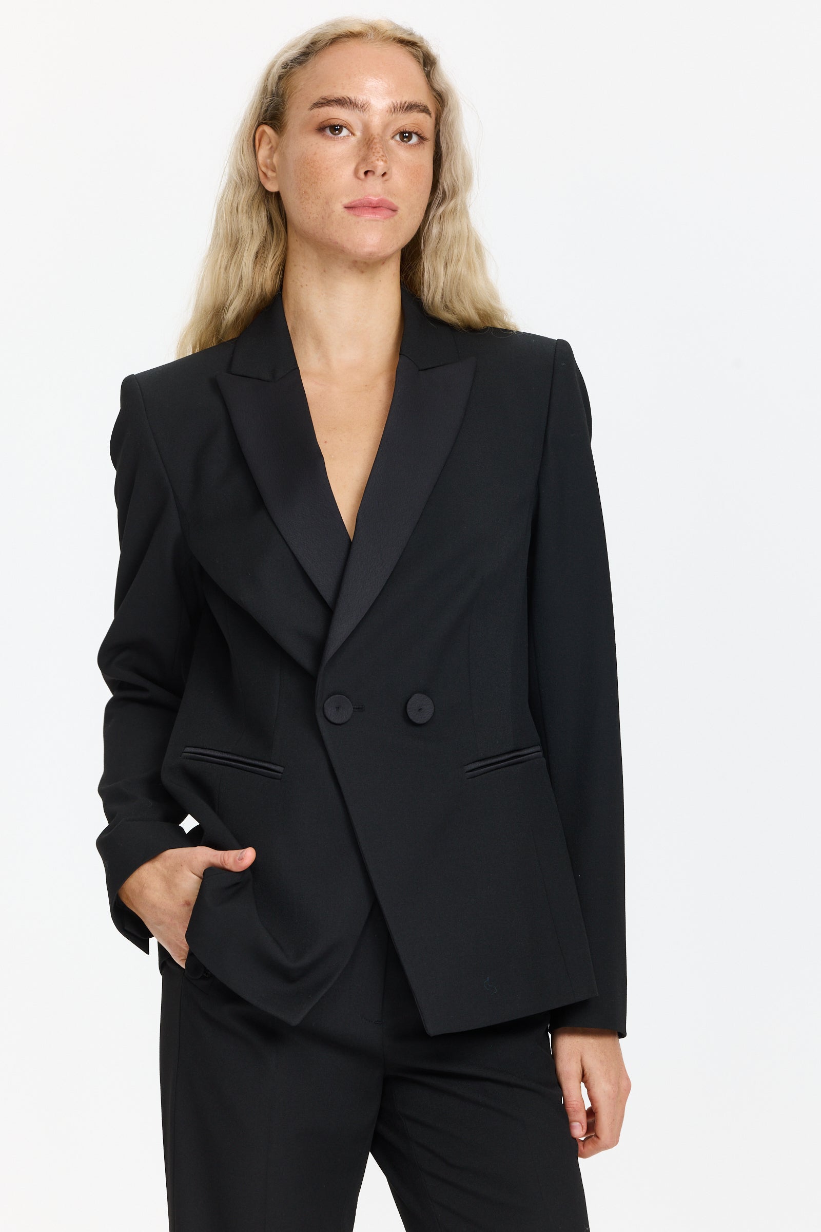 בלייזר טוקסידו בצבע שחור עם סגירה כפולה, שני כיסים וכריות כתףהרכב הבד: 67% פוליאסטר, 29% ויסקוזה, 4% אלסטןהדוגמנית בגובה 1.75 ולובשת מידה 36 של Luisa Cerano