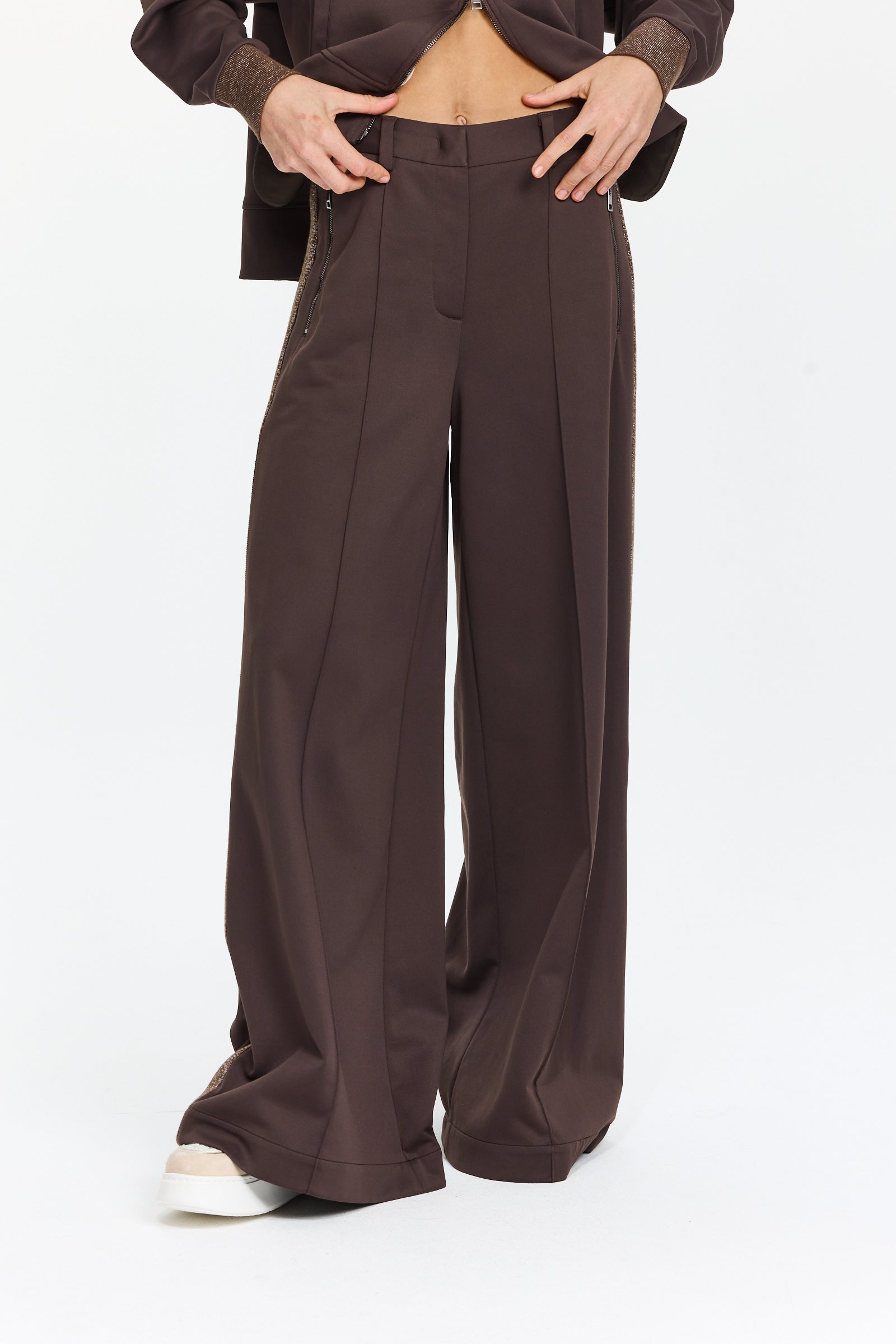 מכנסיים רחבים בצבע חום כהה עם כיסים צדדיים, מעוטרים בפסים מנצנצים לאורך הצדדיםהדוגמנית בגובה 1.75 ולובשת מידה 42 של Lorena Antoniazzi