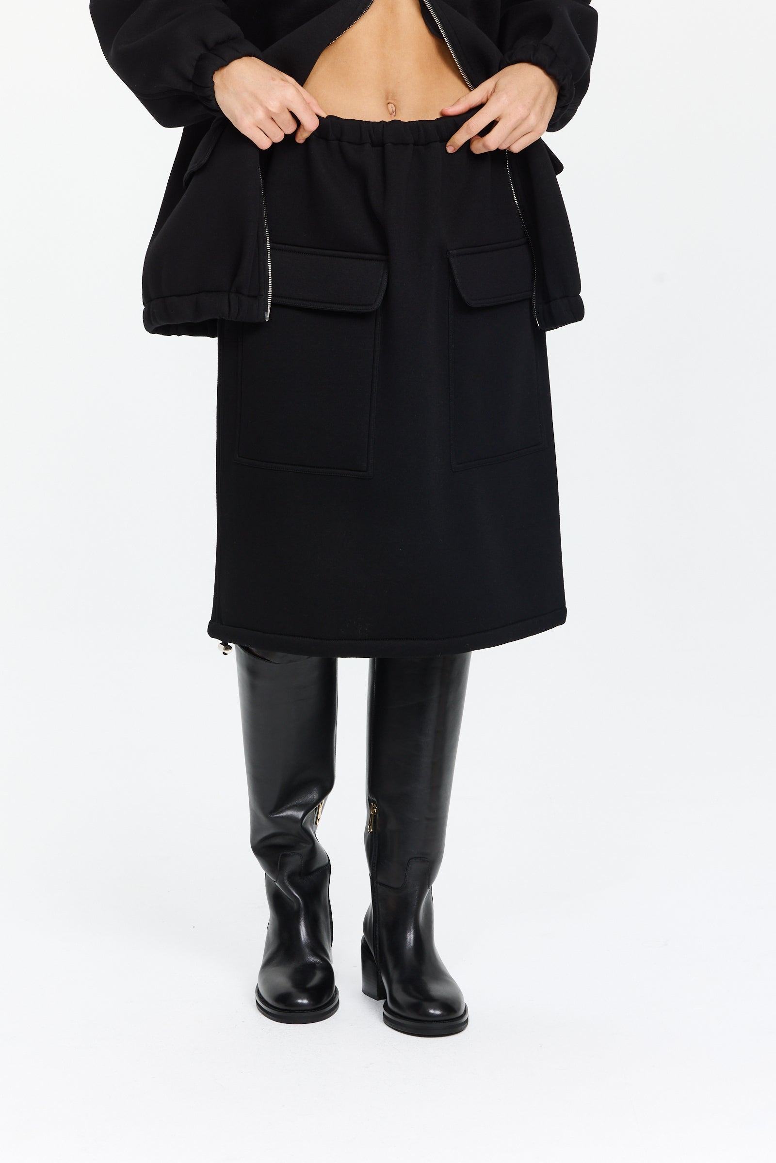 חצאית שחורה באורך מידי עם מותן אלסטית ושני כיסים קדמיים עם דשים, אפשרות לכיווץ בתחתיתהרכב בד: 100% ויסקוזההדוגמנית בגובה 1.75 ולובשת מידה 38 של Plan C