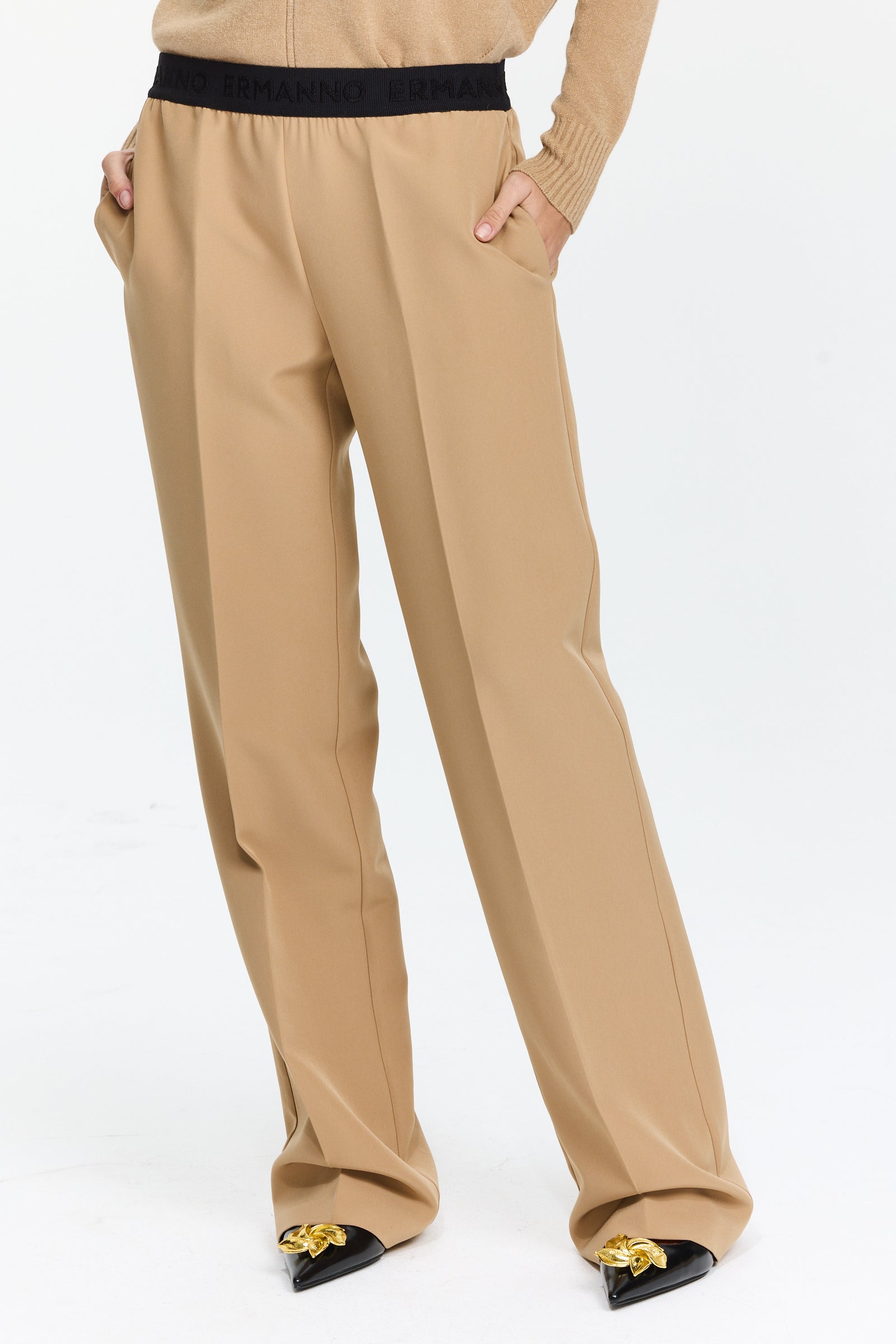מכנסיים בצבע חום בז’ עם חגורת גומי, כיסים צדדיים, קפלים קדמיים וגזרה ישרה עד אמצע המותןהרכב בד: 89% פוליאסטר, 11% אלסטןהדוגמנית בגובה 1.75 ולובשת מידה 42 של Ermanno