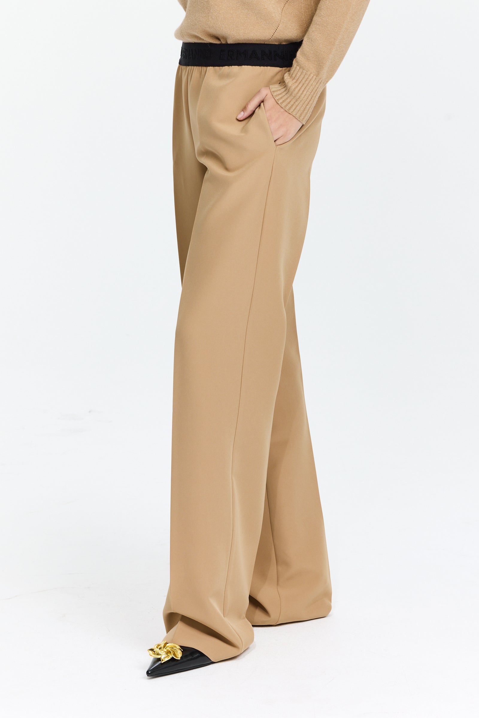 מכנסיים בצבע חום בז’ עם חגורת גומי, כיסים צדדיים, קפלים קדמיים וגזרה ישרה עד אמצע המותןהרכב בד: 89% פוליאסטר, 11% אלסטןהדוגמנית בגובה 1.75 ולובשת מידה 42 של Ermanno