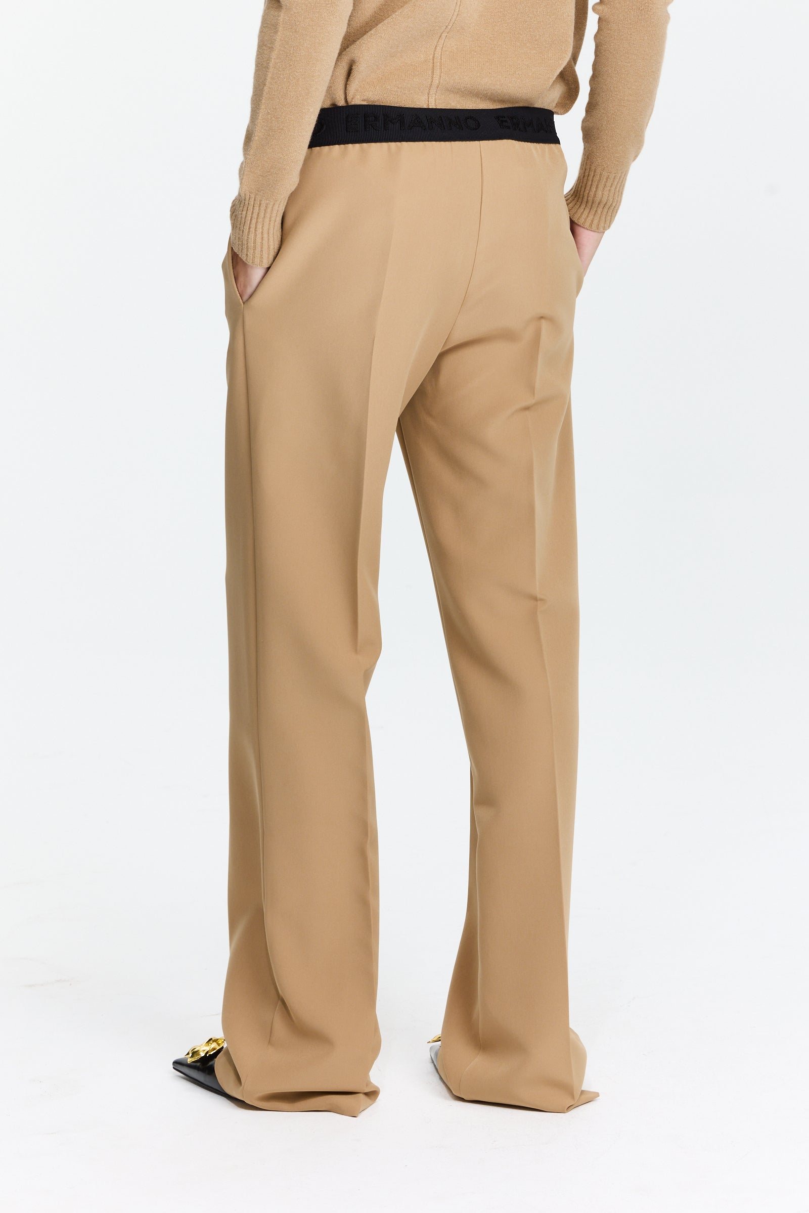 מכנסיים בצבע חום בז’ עם חגורת גומי, כיסים צדדיים, קפלים קדמיים וגזרה ישרה עד אמצע המותןהרכב בד: 89% פוליאסטר, 11% אלסטןהדוגמנית בגובה 1.75 ולובשת מידה 42 של Ermanno