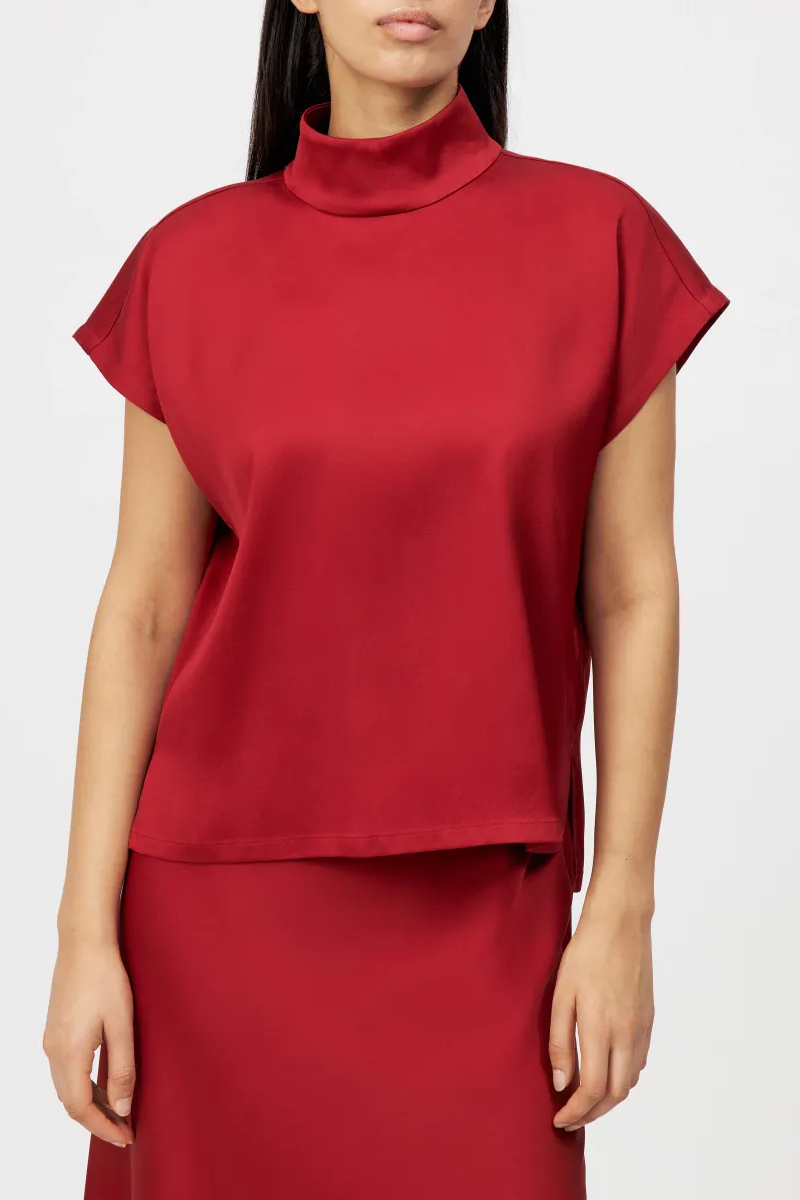 חולצה מבית המותג DRYKORN, בעיצוב קז'ואל-אלגנטי, מבד סאטן איכותי. גזרה נינוחה, עם שרוולים קצרים, וצווארון עומד בסגירת כפתור אחורית.הרכב: 96% אצטט, 4% אלסטןהדוגמנית בגובה 1.78 ולובשת מידה 2 של דרייקורן.