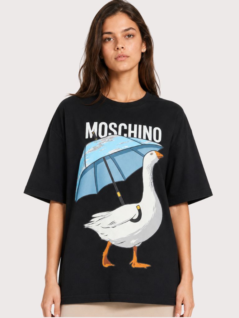 הטישירט האייקונית של MOSCHINO עם האווז אוחז מיטריה.האווז הוא דמות קלאסית בעיצובים של MOSCHINO ורק לאחרונה החזירו אותו לפרונט.בטישירט הזו הוא מקבל מקום של כבוד תחת הלוגו הקלאסי של המותג.הגיזרה היא ישרה ומעט אובר סייז. הרכב: 100% כותנה הדוגמנית 1.80 ולובשת מידה S