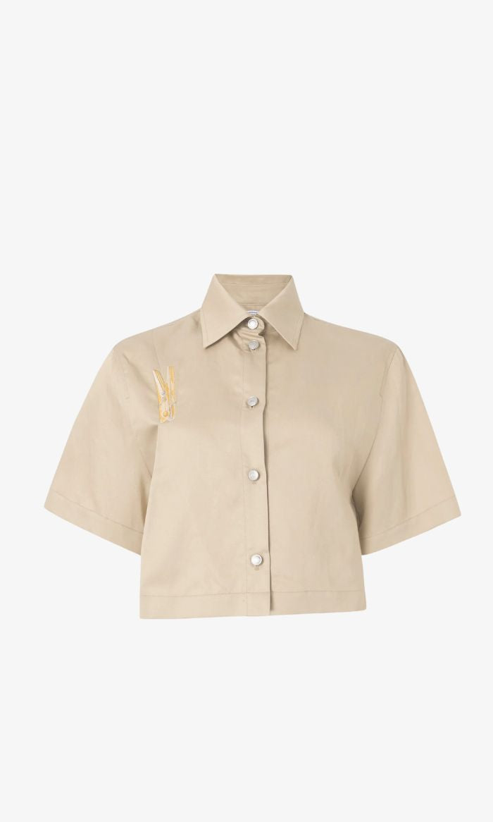 חולצה גזרת קרופ מכופתרת בעיטור אטב מוזהב הרכב: 56% ליוסל, 26% פשתן, 18% כותנההדוגמנית בגובה 1.78 ולובשת מידה 40 של MOSCHINO