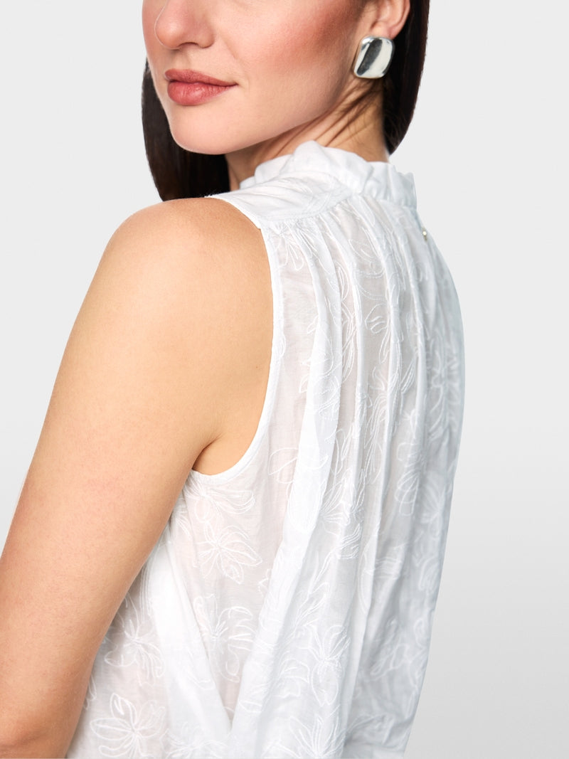 חולצה אלגנטית ללא שרוולים בגזרה רחבה, עשויה בד מעט שקפקף, מתערובת כותנה ומשי רכה וקלילה, עם דוגמת רקמה פרחונית עדינה. קפלים מודגשים בחזית ובגב, וצווארון קולר בגימור מסולסל עם סגירת 3 כפתורים.הרכב: 77% כותנה, 23% משיהדוגמנית בגובה 1.79 ולובשת מידה 3 של מארק קיין 