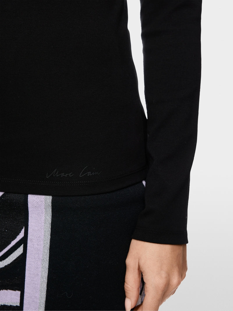 חולצה זו בגזרה צרה (Slim fit) עם שרוולים ארוכים משלבת כותנה סטרצ'ית איכותית עם פרטים אקסקלוסיביים. הגזרה הצמודה לגוף מבטיחה סילואט עכשווי ונוחות מעולה. פרט ייחודי: קו הצוואר העגול הקלאסי, המקבל מראה אלגנטי הודות לשוליים דו-שכבתיים ממשי טהור.עיצוב בגזרה צרה, שרוולים ארוכים, קו צוואר עגול, וכיתוב Marc Cain.הרכב: 92% כותנה, 8% אלסטןפתיון: 100% משיהדוגמנית בגובה 1.79 ולובשת מידה 3 של מארק קיין