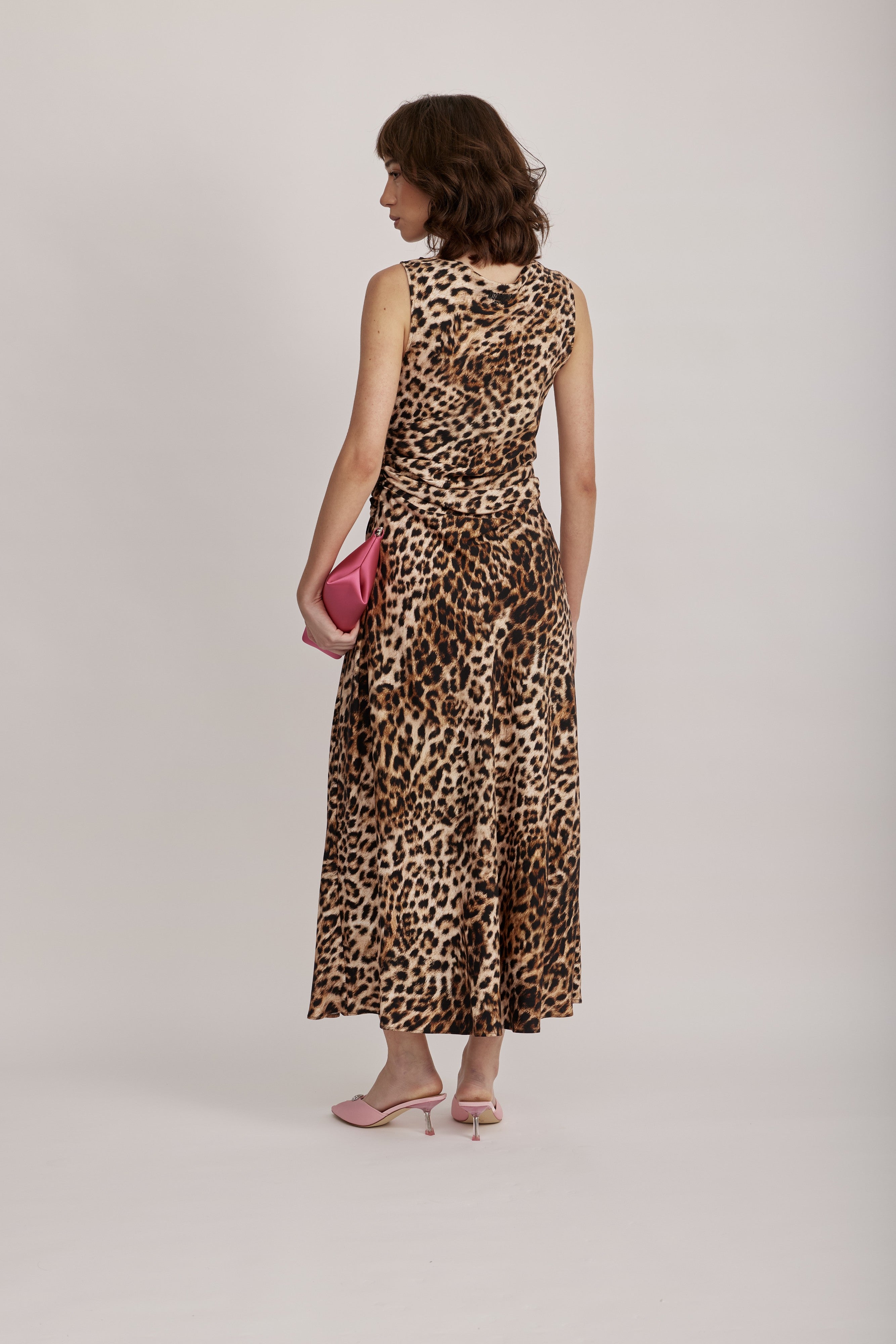 שמלת מקסי מליין MOSCHINO JEANS של המותג האיטלקי מוסקינו.שמלה בעיצוב אלגנטי ונועז, מבד ויסקוזה קליל בהדפס דוגמה מנומרת. ללא שרוולים, עם צווארון סירה, קפלים מכווצים בצד המותן וחצאית מתרחבת יוצרים צללית קלאסית ונשית. לוגו המותג מוטבע בגב השמלה.הרכב: 100% ויסקוזההדוגמנית בגובה 1.75 ולובשת מידה 42 של MOSCHINO