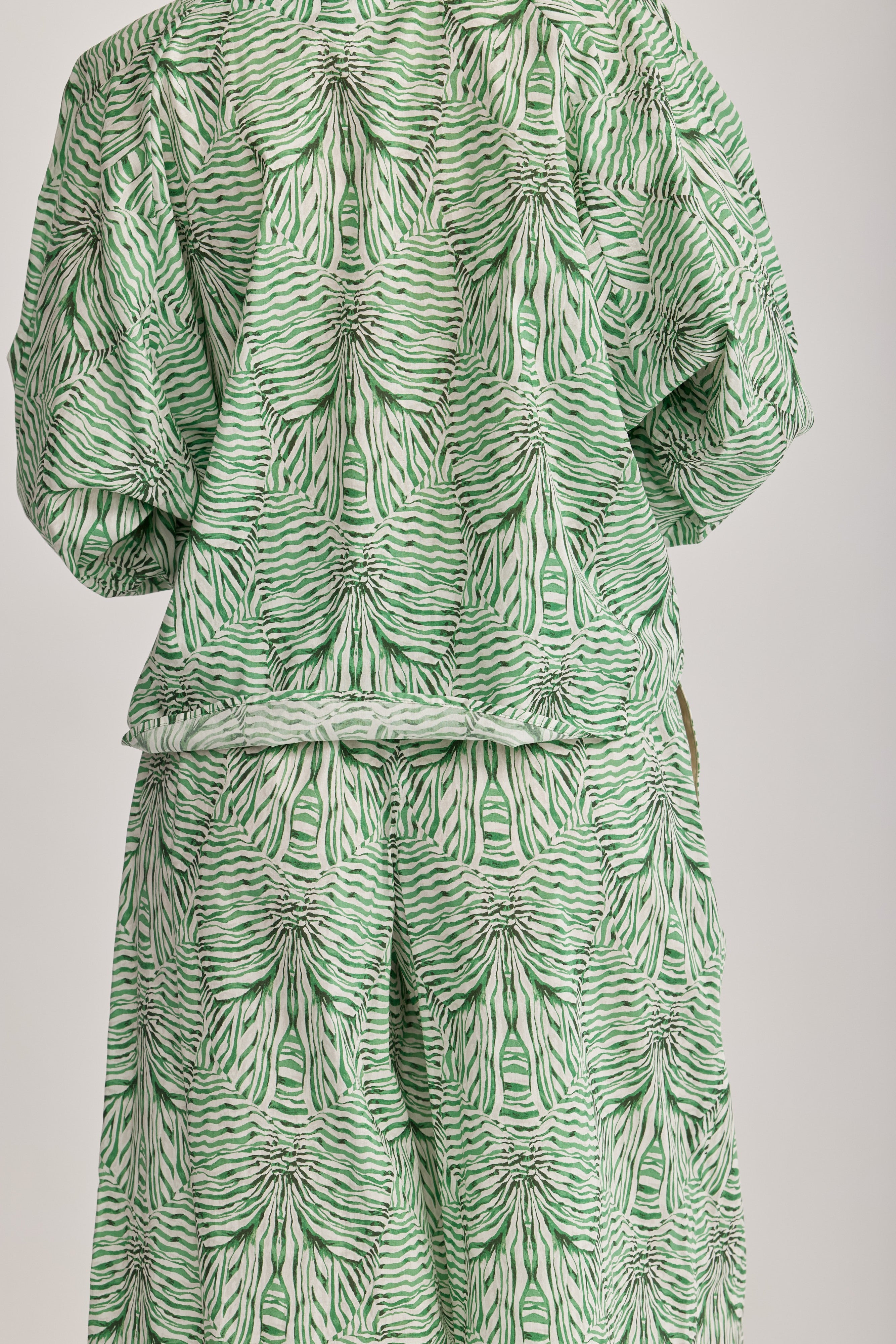 חולצה מבית המותג DRYKORN, מבד כותנה קליל בהדפס בגוון ירוק. החולצה בגזרה רחבה ונינוחה, עם שרוולים ארוכים, צווארון עגול עם קפלים מודגשים סביב הצוואר, וסגירת כפתור.הרכב: 100% כותנההדוגמנית בגובה 1.75 ולובשת מידה 2 של דרייקורן