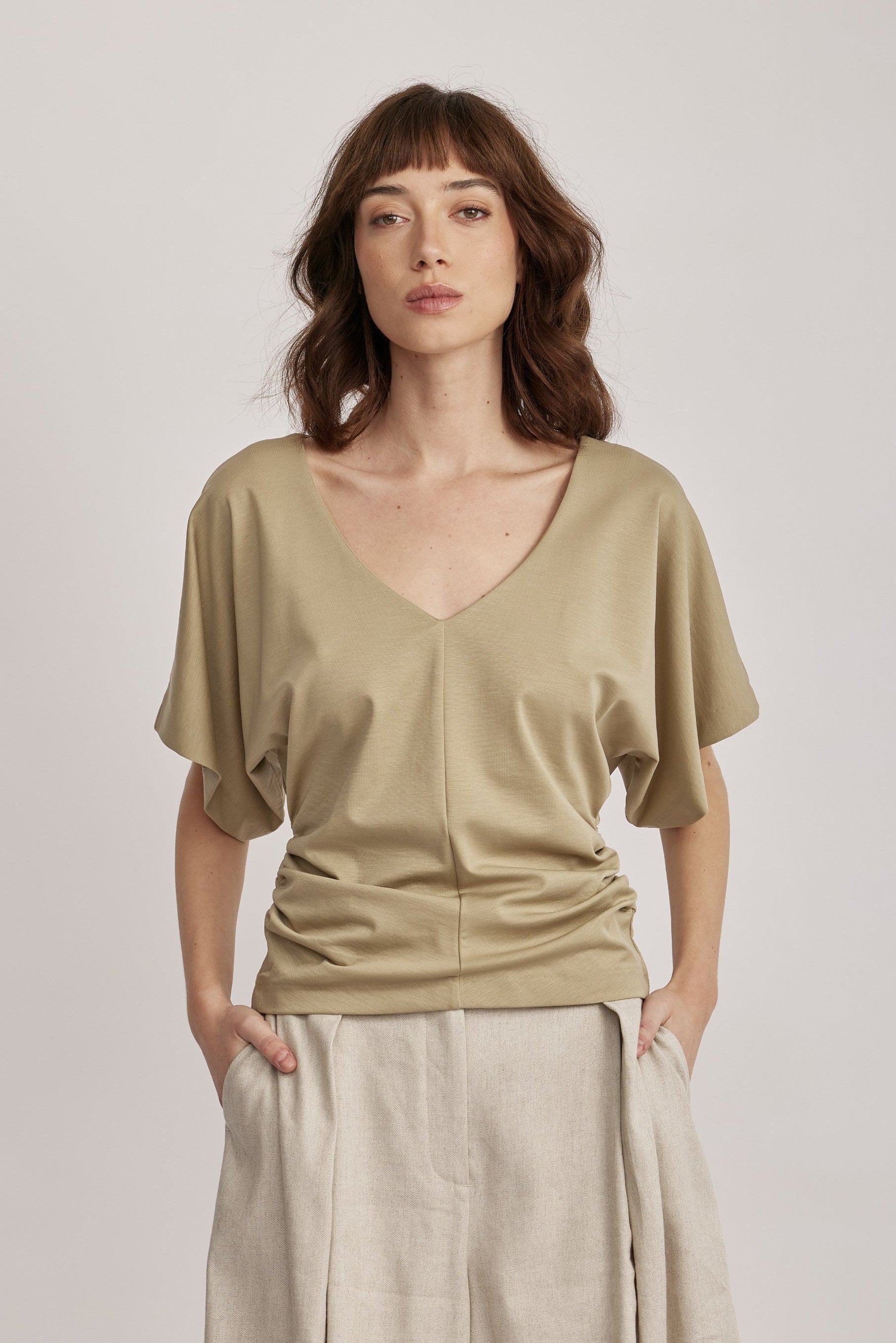 חולצה מבית המותג DRYKORN, מבד רך ונעים. גזרה נינוחה, עם שרוולי עטלף קצרים, צווארון וי, דוגמת כיווצים בצידי החולצה, ותפר אמצעי מודגש בחזית.הרכב: 73% ליוסל, 23% פוליאמיד, 4% אלסטןהדוגמנית בגובה 1.78 ולובשת מידה S של דרייקורן.