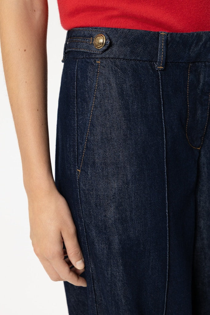 ג'ינס רחב מבית המותג Luisa Cerano, מבד דנים אותנטי, רך ונעים. מכנסיים בגזרת Wide Leg נוחה ואופנתית, עם שני כיסי צד ושני כיסי צ'ינו אחוריים, תפרים קדמיים מודגשים, עיטור כפתורים דקורטיביים במותן, לולאות לחגורה, וסגירה נסתרת באמצעות רוכסן וכפתור.הרכב בד: 81% כותנה, 19% ליוסל (Tencel)הדוגמנית בגובה 1.78 ולובשת מידה 36 של Luisa Cerano