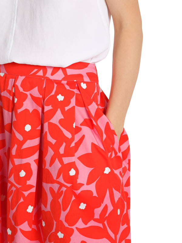 חצאית אורך ברך עשויה כפלים בהדפס פרחים ורודים על רקע אדום
