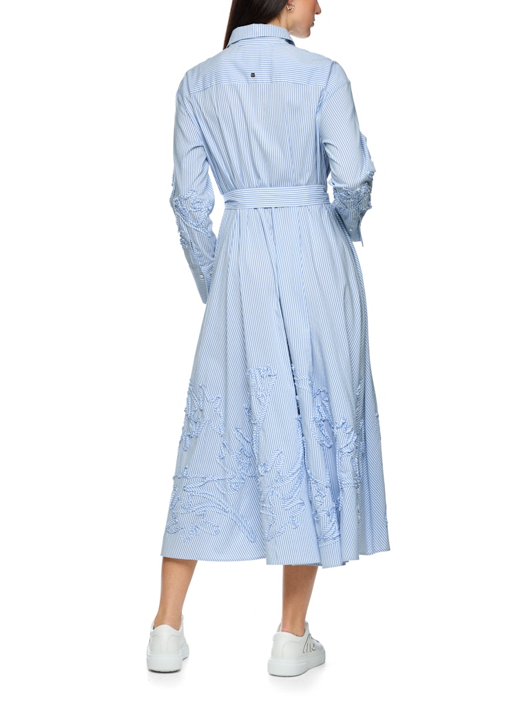 שמלת מידי בעיצוב קז'ואל-אלגנטי, עשויה בד רך וקליל בדוגמת פסים בגווני תכלת ולבן. גזרה נינוחה, עם חגורת מותן נלווית הניתנת לקשירה, להדגשת הצללית הנשית. חצאית מתרחבת, עם נפילה עשירה וזורמת. תוספת דיטייל של עיטור רקמה בדוגמה פרחונית בשרוולים ובחצאית מעניקה לשמלה טוויסט מודרני וייחודי.סגירת כפתורים נסתרת לכל האורך, צווארון קלאסי, ושרוולים ארוכים בסיומת חפתים מכופתרים רחבים המאפשרים התאמת אורך אישית.הרכב: 65% כותנה, 32% פוליאסטר, 3% אלסטןהדוגמנית בגובה 1.79 ולובשת מידה 3 של מארק קיין