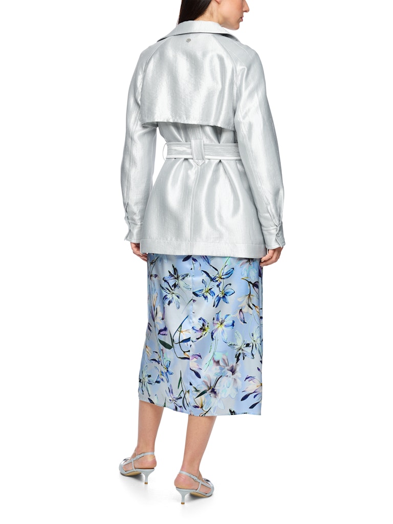 ז'קט בעיצוב מעיל טרנץ' אופנתי, עשוי בד מתערובת ויסקוזה רכה ועמידה, עם ברק כסוף עדין.גזרה נינוחה, עם חגורת מותן נלווית הניתנת לקשירה או לסגירה באמצעות אבזם, בטנה דקה, כיסי צד, ורכיסת כפתורים כפולה.הרכב: 67% ויסקוזה, 19% פוליאמיד, 14% פוליאסטרהדוגמנית בגובה 1.79 ולובשת מידה 3 של מארק קיין