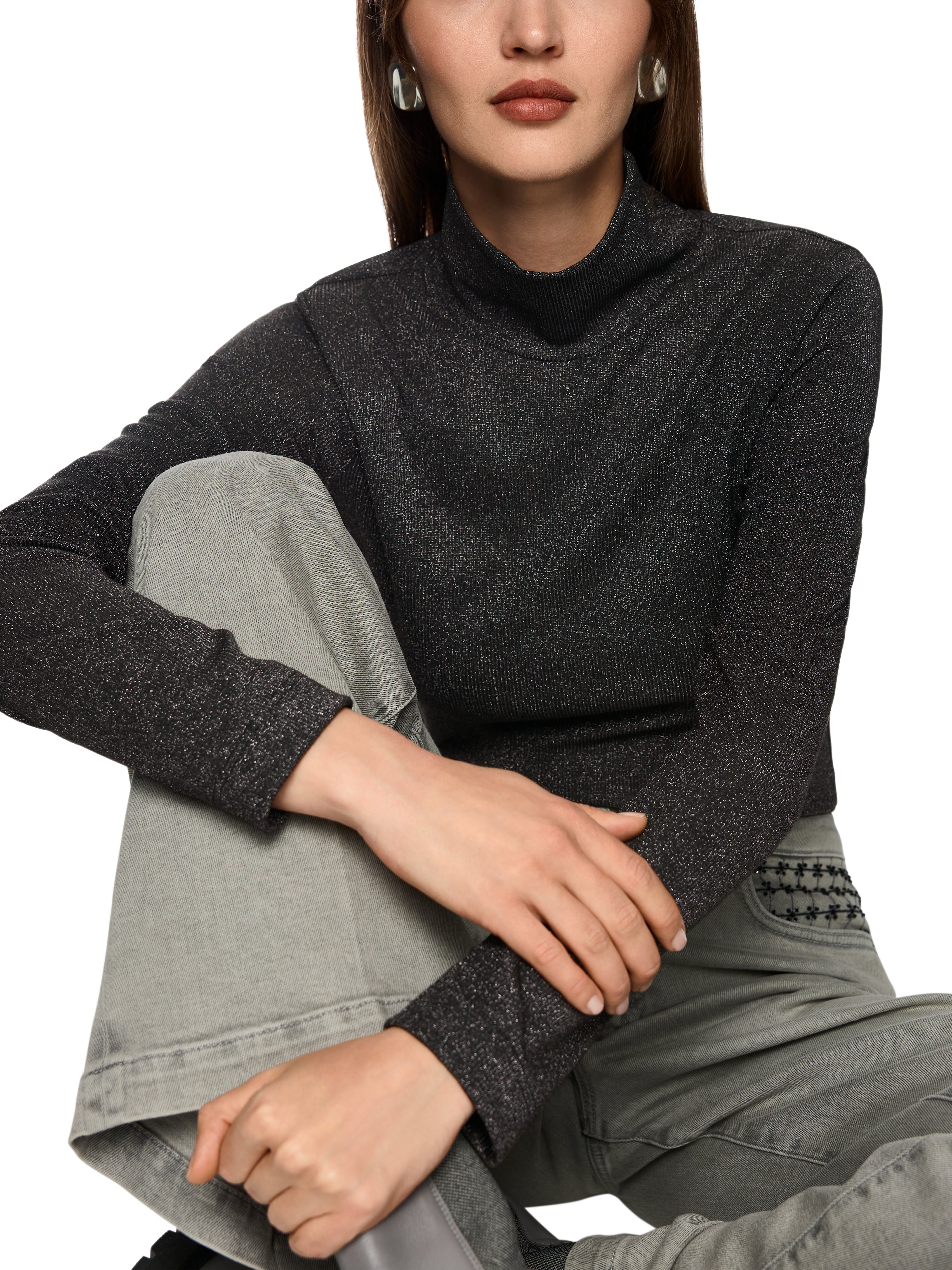 חולצה עם שרוולים ארוכים, לורקס מנצנץ וצווארון גבוה. גזרה צמודה ובד גמיש, בגוון אפור כהההרכב בד: 66% פוליאסטר, 17% סיב מתכתי, 15% פוליאמיד, 2% אלסטןהדוגמנית בגובה 1.79 ולובשת מידה 3 של מארק קיין