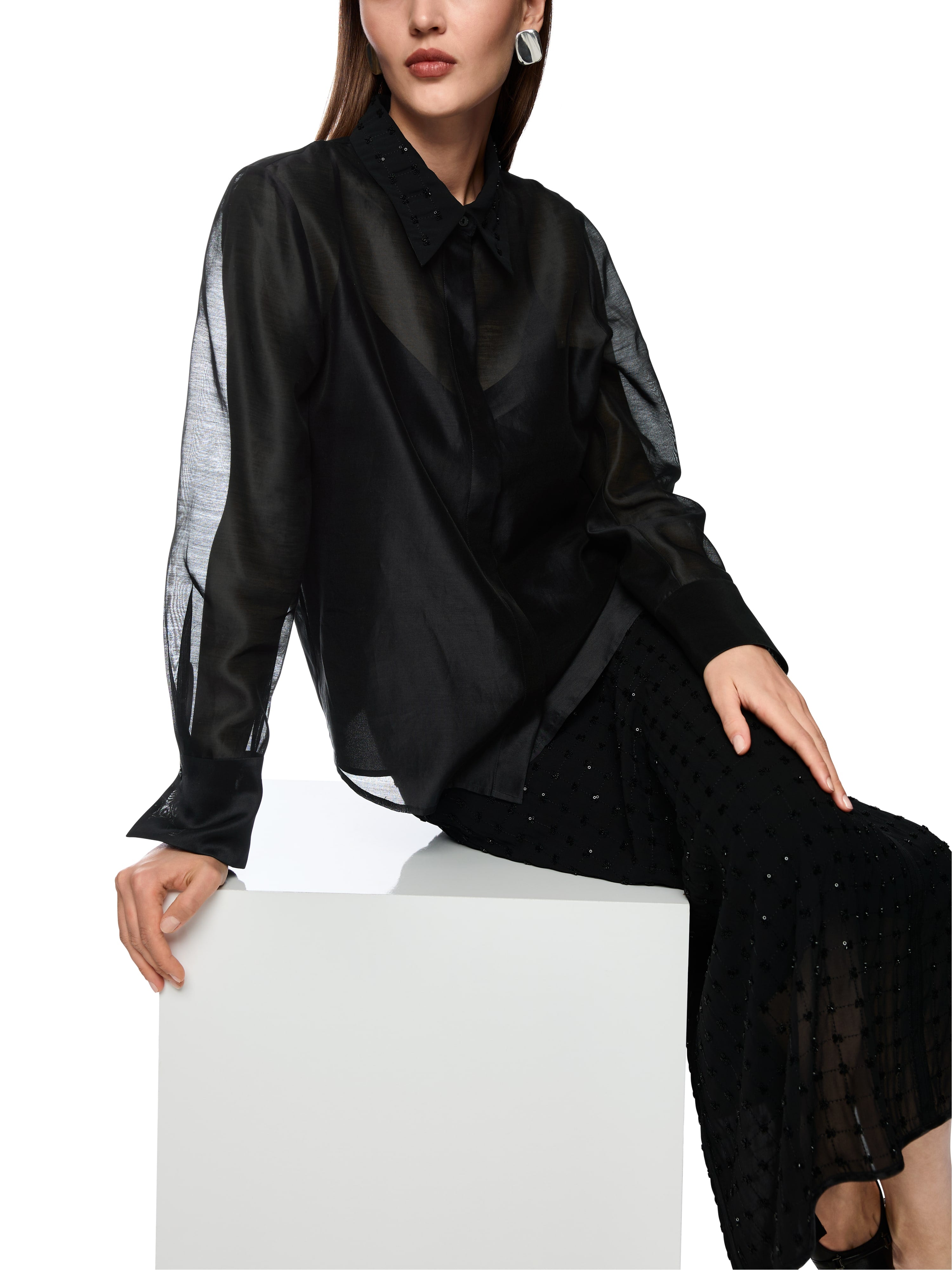 חולצת אורגנזה שקופה עם רקמה עדינה בצווארון, בגזרה רחבה עם תחתית חלקה וחלק שקוף בחלקה העליון.הרכב בד: 79% כותנה, 21% משיהדוגמנית בגובה 1.79 ולובשת מידה 3 של מארק קיין