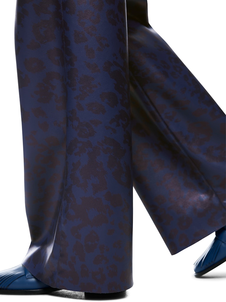 מכנסיים בגזרה רחבה, עשויים בד רך דמוי עור עם ברק עדין, בגוון כחול כהה והדפס דוגמה מנומרת. עם מותן גבוהה, שני כיסי צד ושני כיסים אחוריים, לולאות לחגורה, וסגירה באמצעות וו ורוכסן.הרכב: 100% פוליאסטר, ציפוי פוליאוריטןהדוגמנית בגובה 1.79 ולובשת מידה 3 של מארק קיין