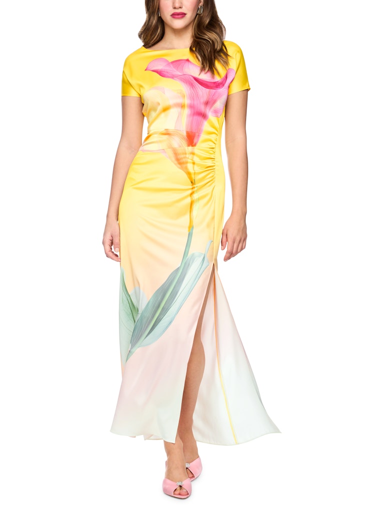 שמלת מקסי אלגנטית, בגזרה צמודה לגוף, עשויה בד סאטן רך וזורם, עם הדפס חזיתי גדול של פרח קאלה. עם שרוולים קצרים, וצווארון עגול, קפלים עדינים בצד המותן מדגישים את הצללית הנשית, ושסע ארוך בצד הרגל מעניק מראה עדכני וחופש תנועה. סגירה באמצעות רוכסן אחורי נסתר.הרכב: 51% פוליאסטר ממוחזר, 49% פוליאסטרהדוגמנית בגובה 1.79 ולובשת מידה 3 של מארק קיין