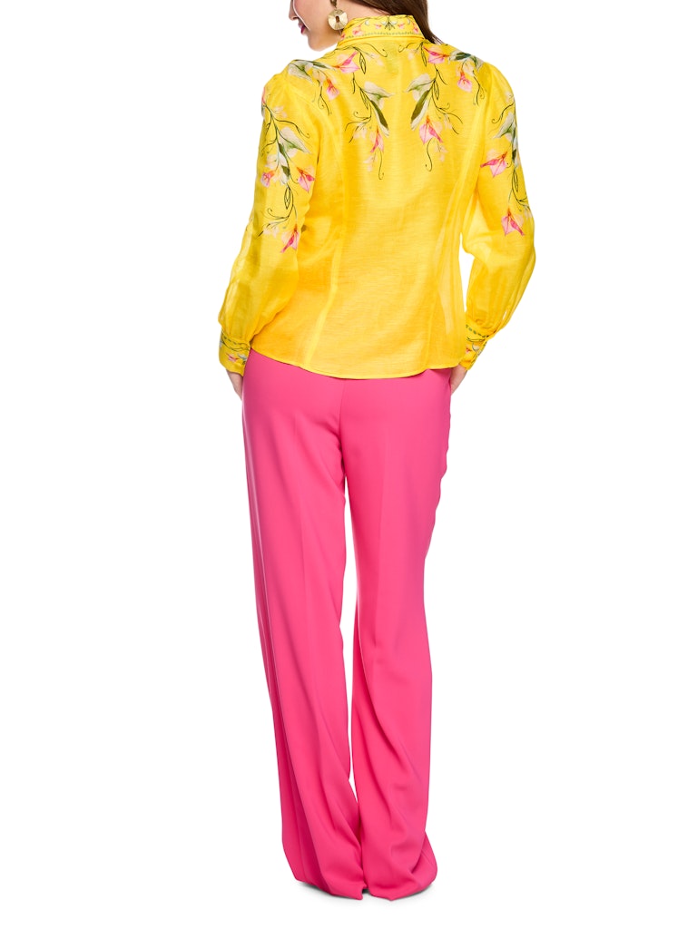 חולצה מכופתרת קלילה ואלגנטית, עשויה תערובת פשתן ומשי איכותית ונעימה. גזרה נשית ונינוחה, עם צווארון קלאסי, שרוולים ארוכים בסיומת חפתים רחבים מכופתרים, וסגירה באמצעות שורת כפתורים קדמית. הדפס צבעוני של דוגמת פרחי קאלה המעטר את החלק העליון של החולצה, הצווארון, והחפתים, מדגיש את העיצוב הייחודי.הרכב: 55% פשתן, 45% משיהדוגמנית בגובה 1.79 ולובשת מידה 3 של מארק קיין